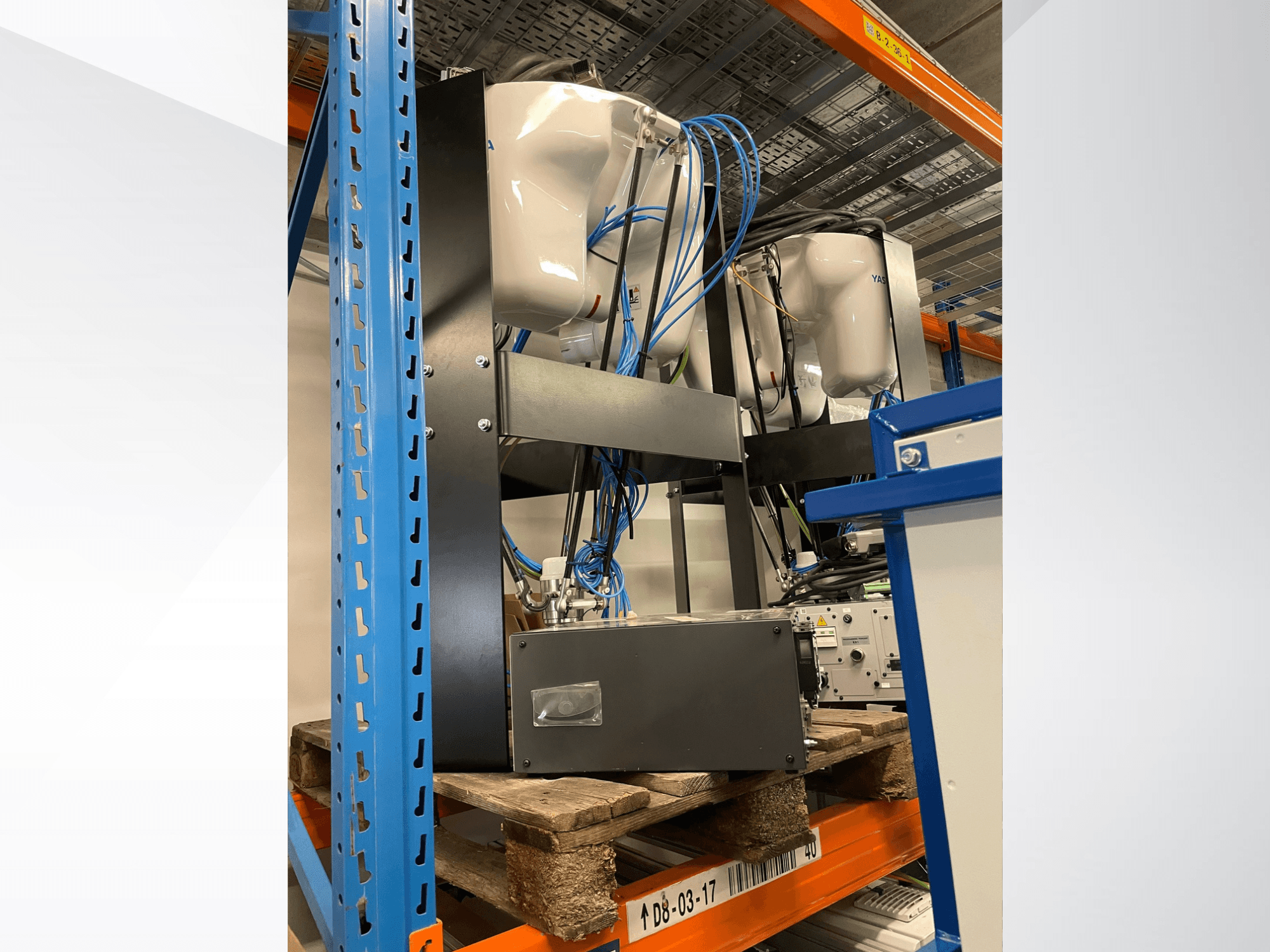 Роботизована рука Yaskawa Motoman MPP3H, зображена у боковому ракурсі, з провідним кабелем та компонентами, що видно на стелажі для зберігання.