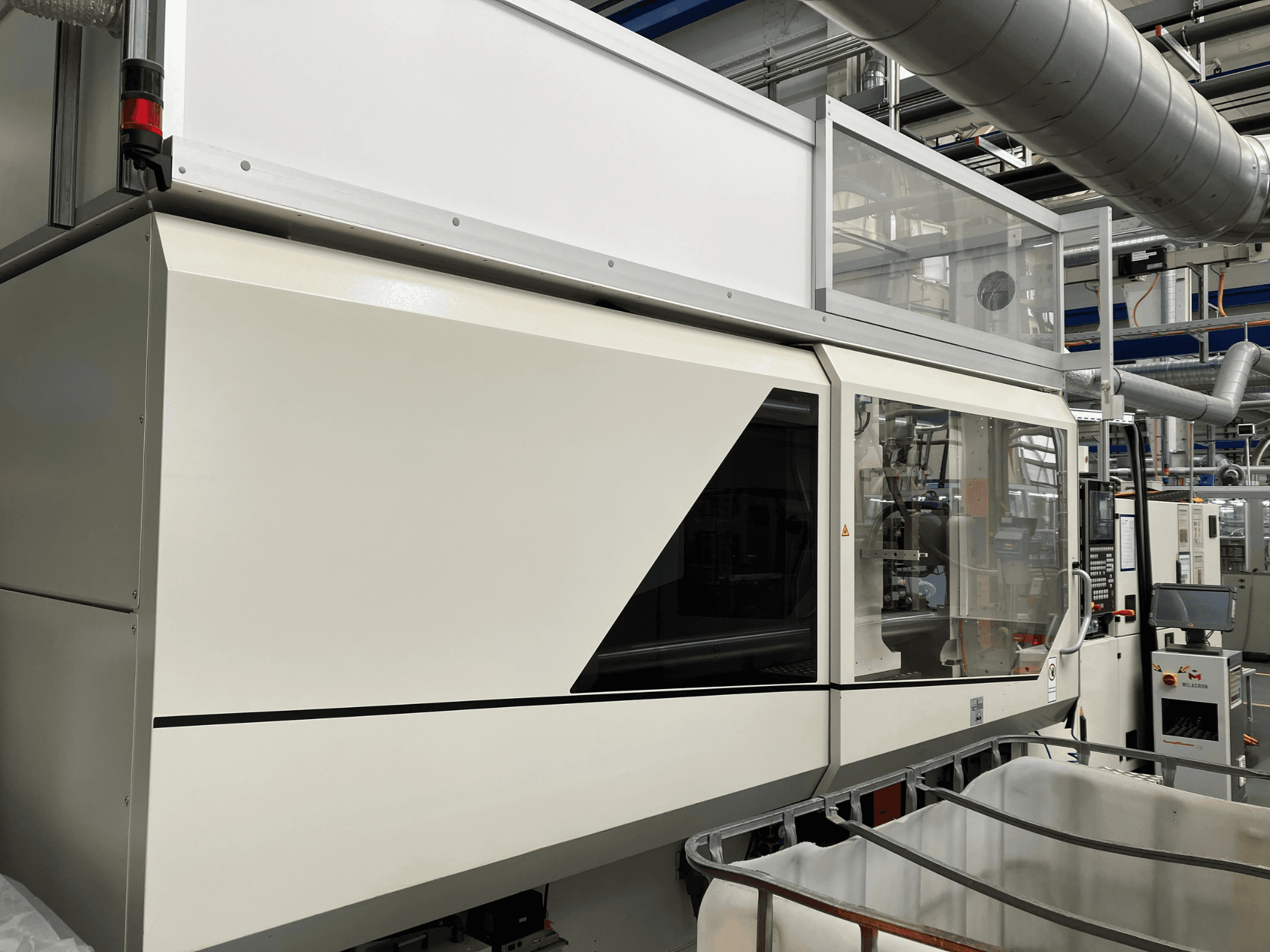 Вид спереду промислового верстата з елегантним білим дизайном, дисплейною панеллю та скляною секцією для видимості компонентів.