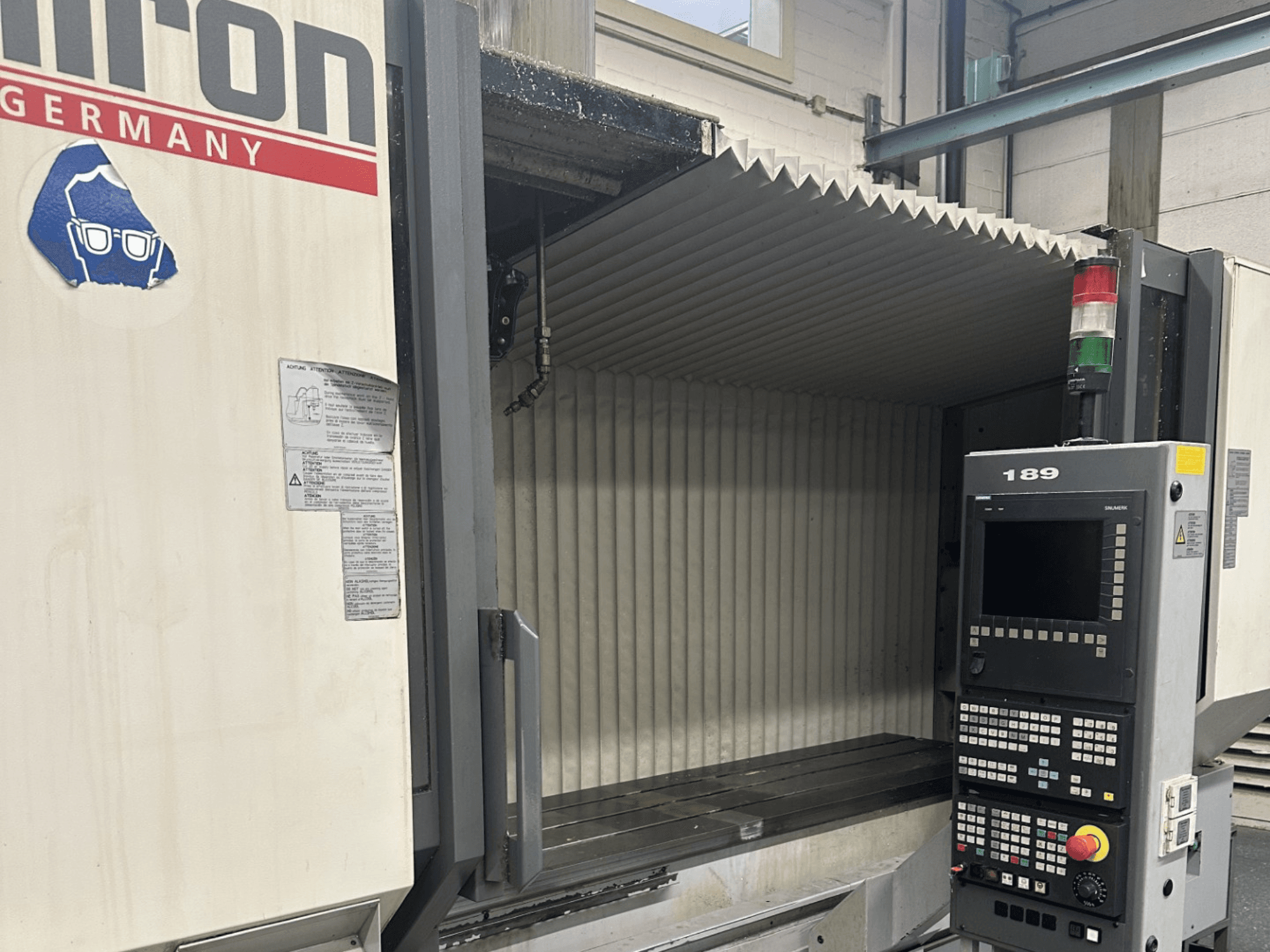 Альтернативний текст: Вид спереду верстата з ЧПК Hermle з панеллю керування з кнопками та дисплеєм, з відкритою робочою зоною.