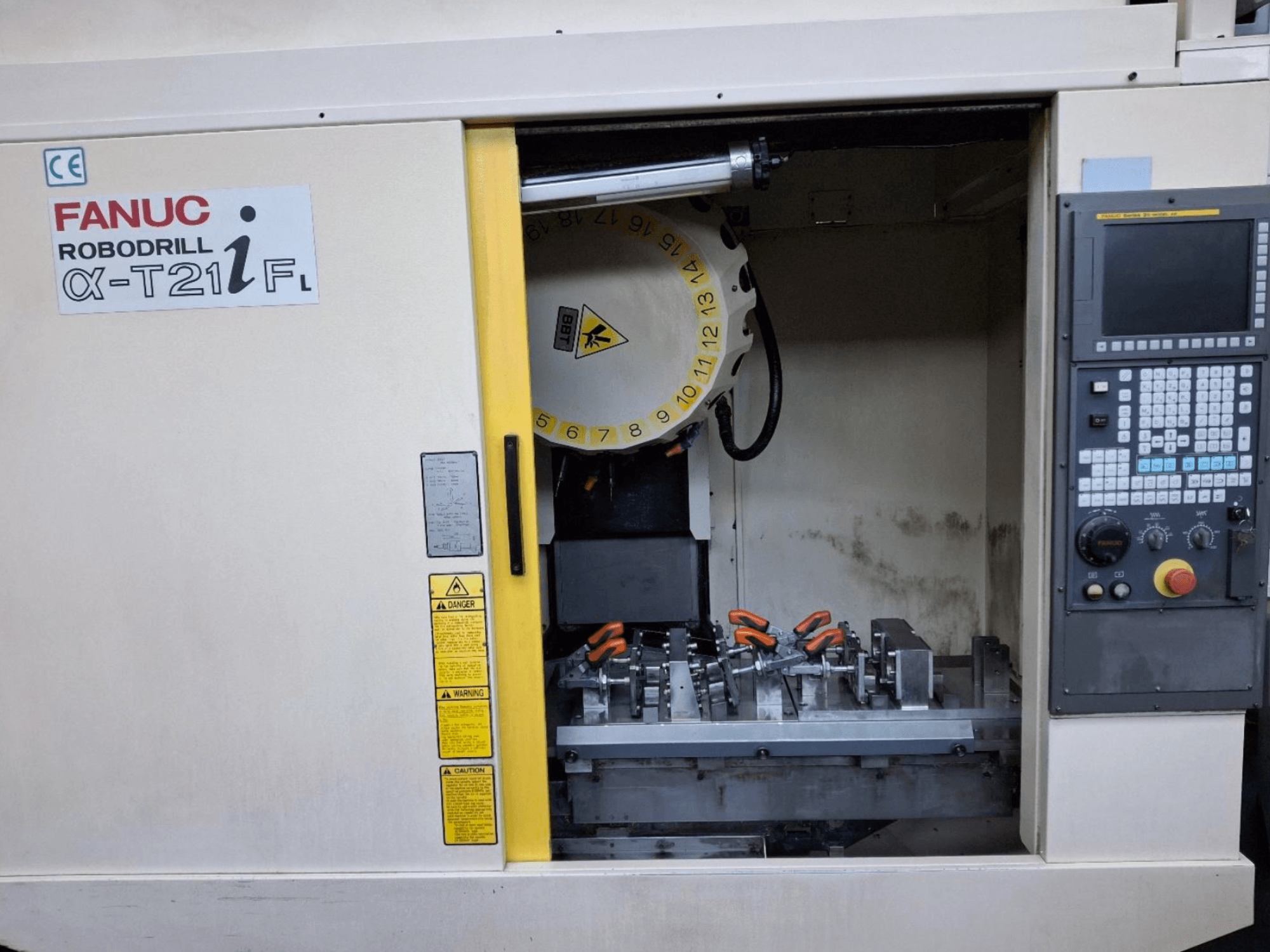 Вертикальний обробний центр FANUC ROBODRILL α-T21iFL - вигляд спереду, показано інструменти та елементи керування всередині шафи.