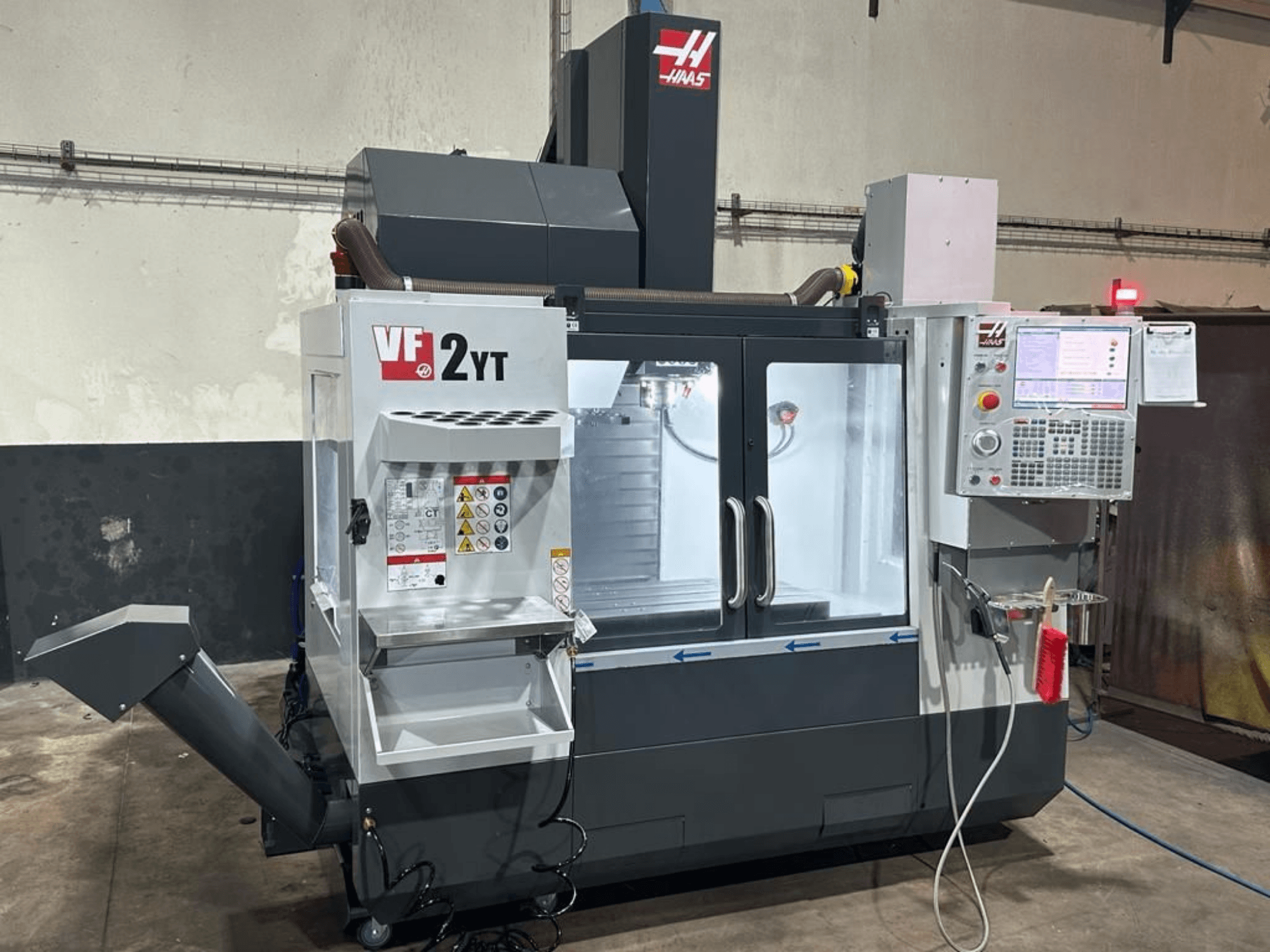 Вертикальний обробний центр HAAS VF-2YT-EU у фронтальному ракурсі, на якому видно панель управління та відсік для зберігання інструментів.