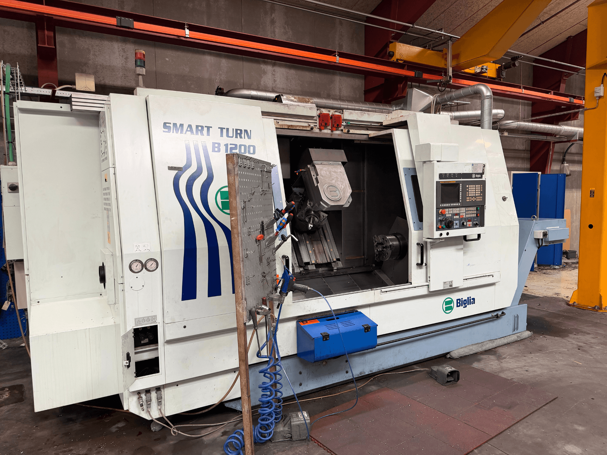 Токарно-фрезерний центр Biglia B.1200/S-Smart у фронтальному ракурсі; на фото видно органи управління, заготовку в шпинделі та манометри.