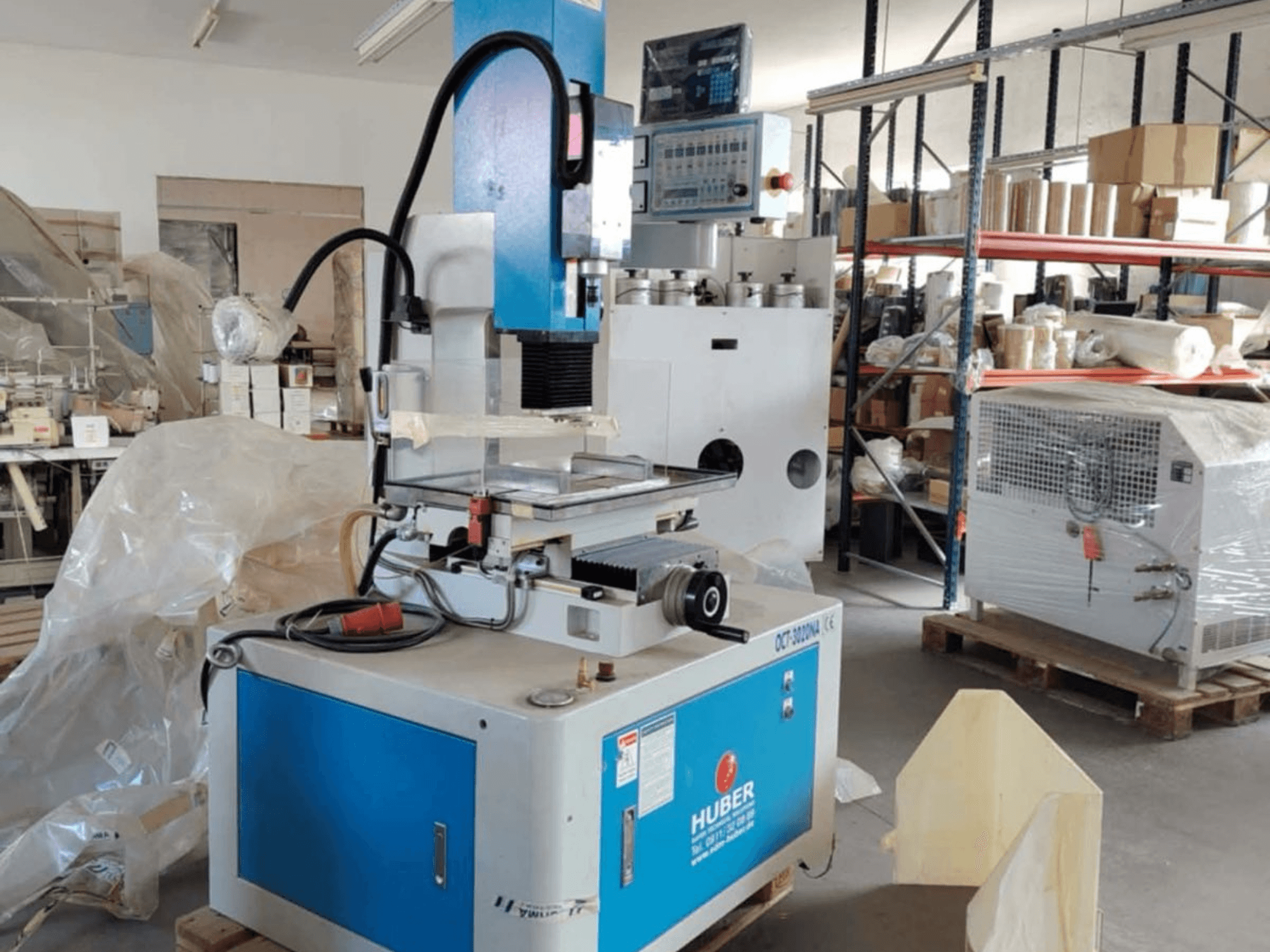Електроерозійний висікальний верстат HUBER OCT-3020 NA в майстерні, вид спереду: синьо-сірий корпус, цифрове керування та робоча зона.