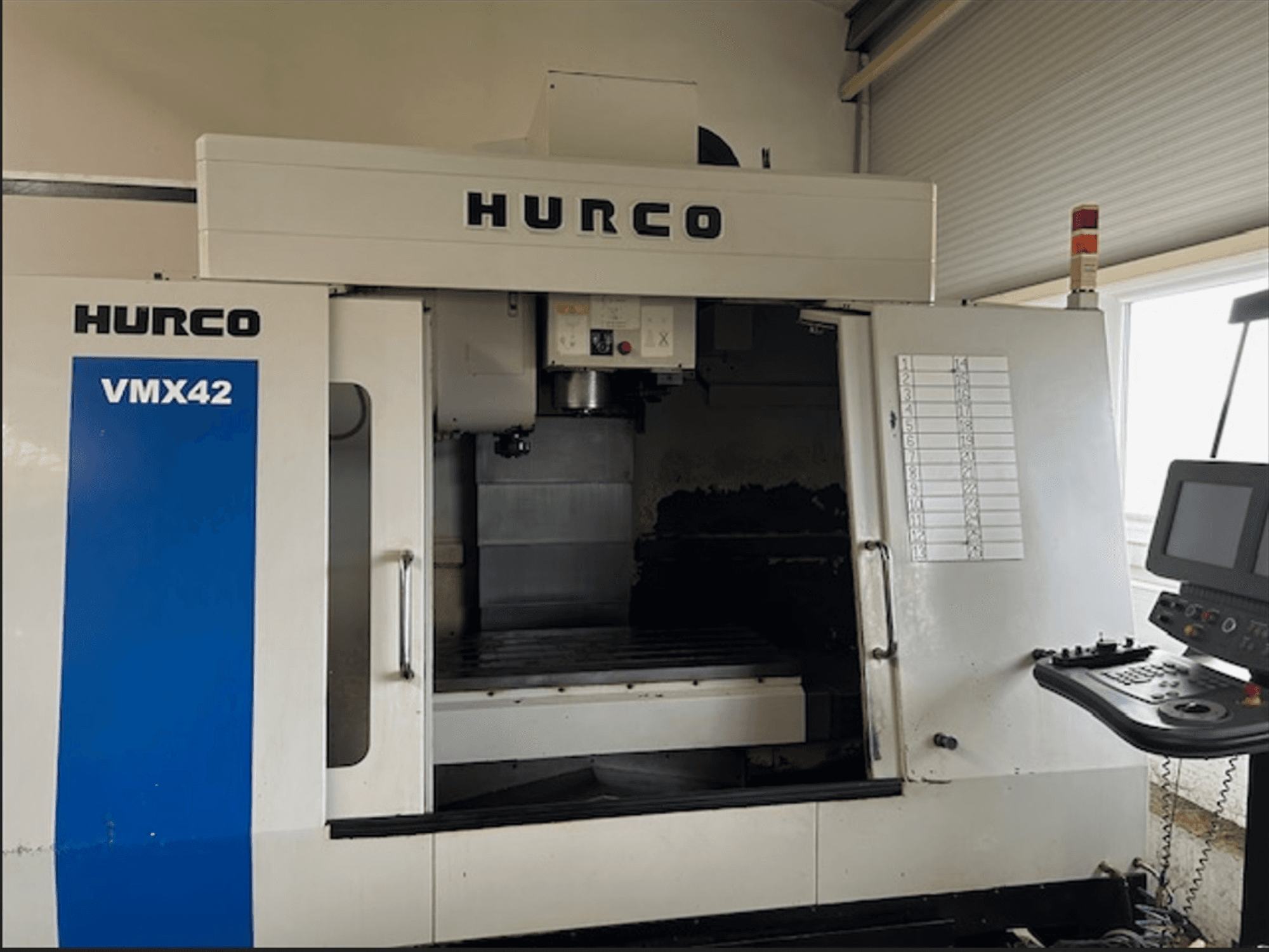 Фрезерний верстат з ЧПК Hurco VMX42, вид спереду, з панеллю керування та відкритим робочим простором для виконання операцій обробки.