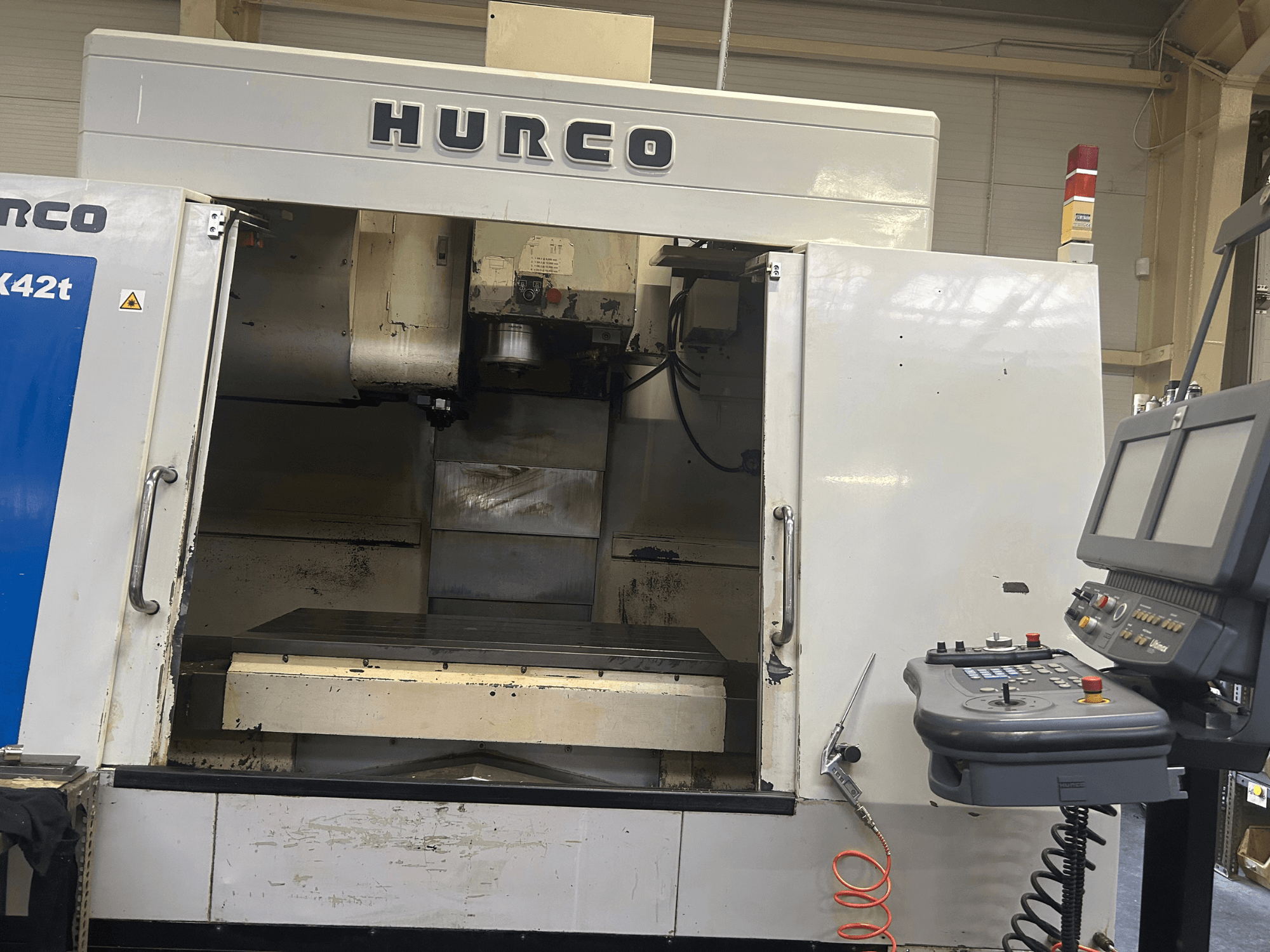 Фрезерний верстат з ЧПК Hurco VMX42T спереду, з відкритим робочим простором і панеллю керування з кнопками та дисплеєм.