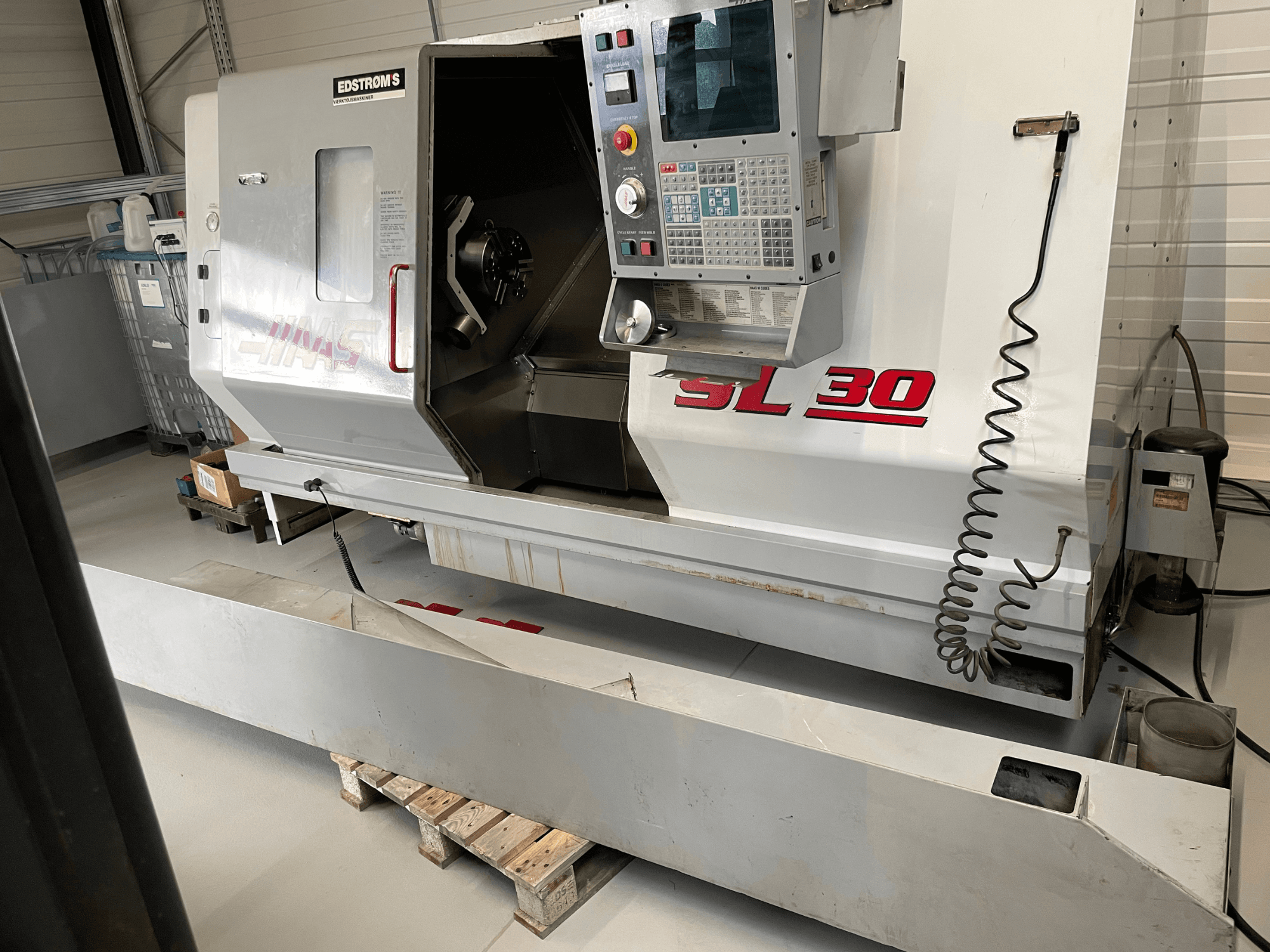 Токарний верстат з ЧПК Haas SL 30 в майстерні, вид збоку, з панеллю керування та відкритим шпинделем для виконання завдань з обробки.