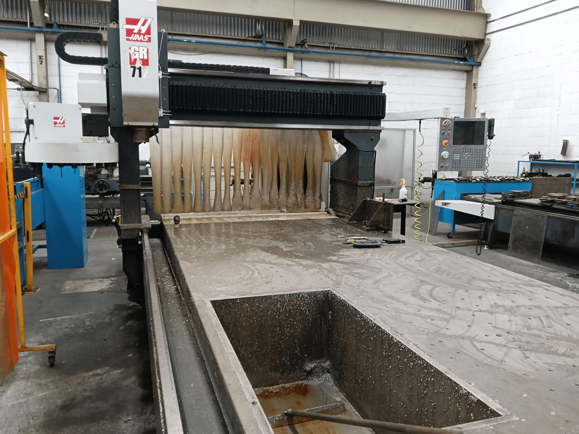 Портальний фрезерний верстат HAAS GR-712, вид спереду, на якому видно робочу поверхню з водяним охолодженням та панель управління оператора.