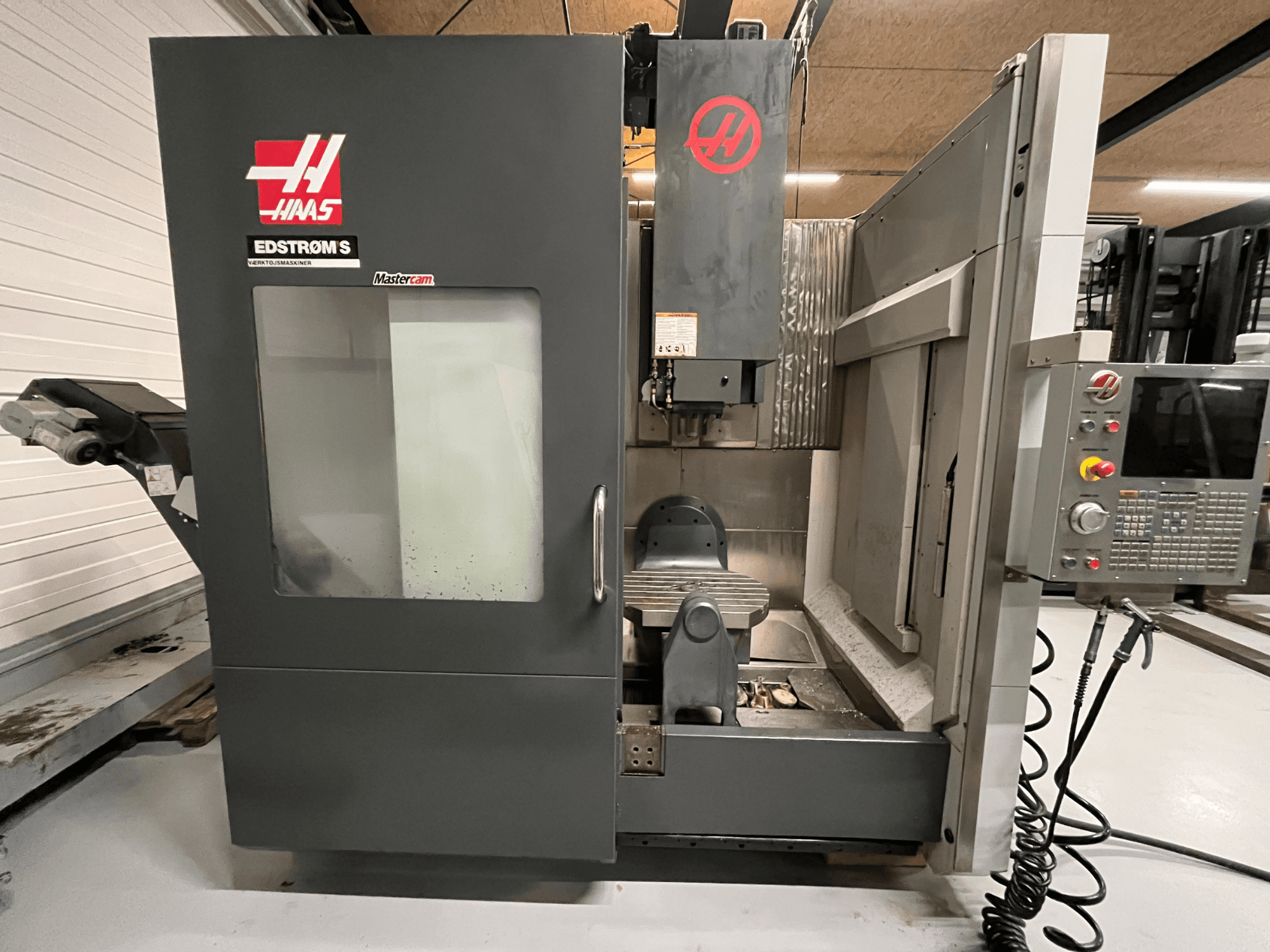 Вид спереду верстата з ЧПК Haas EDSTROM S з панеллю керування, шпиндельною головкою та обробним столом.