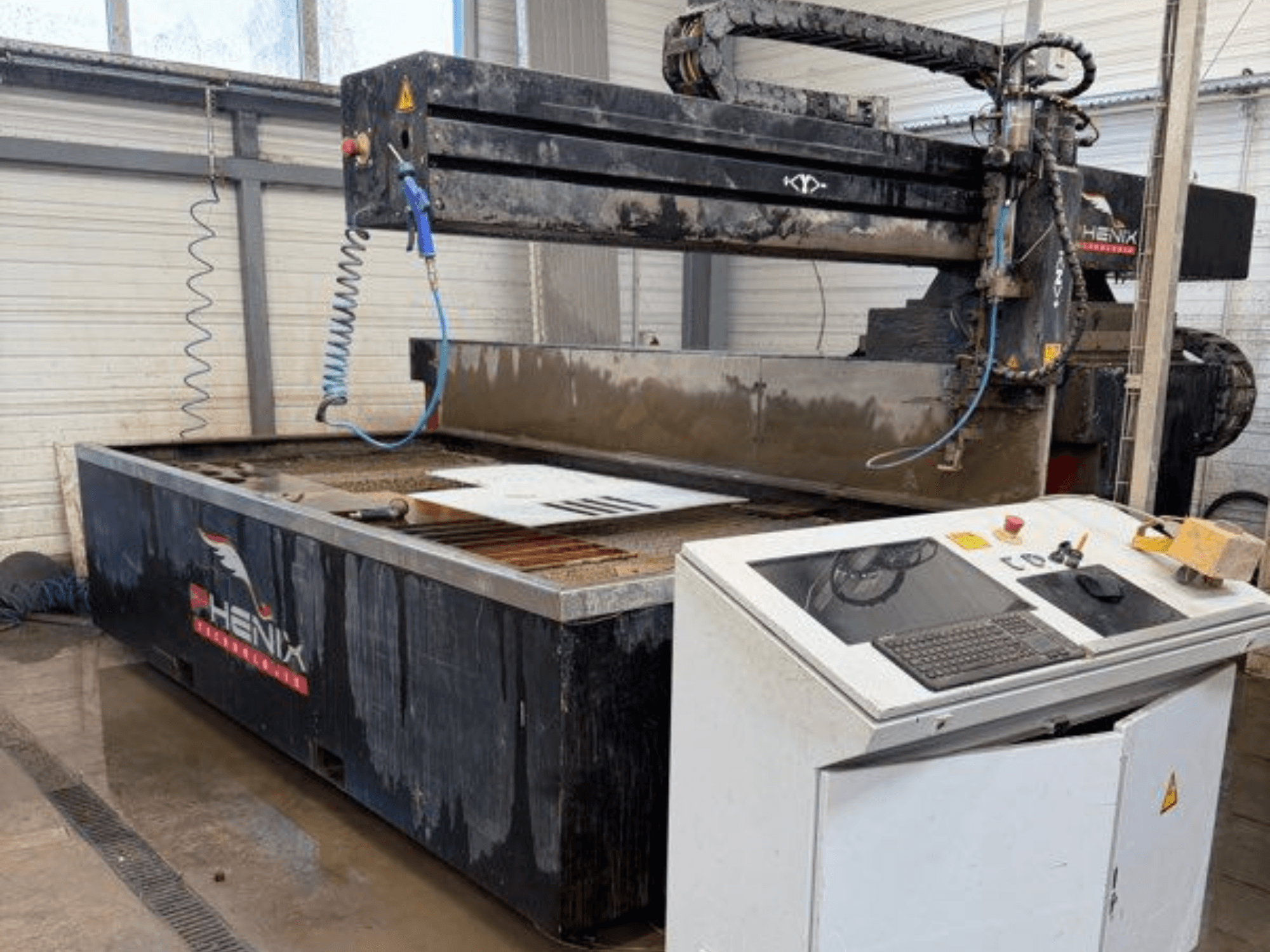 Машина гідроабразивного різання PHENIX MD JET 1530, вид спереду з панеллю керування та зоною різання з видимим баком для води.