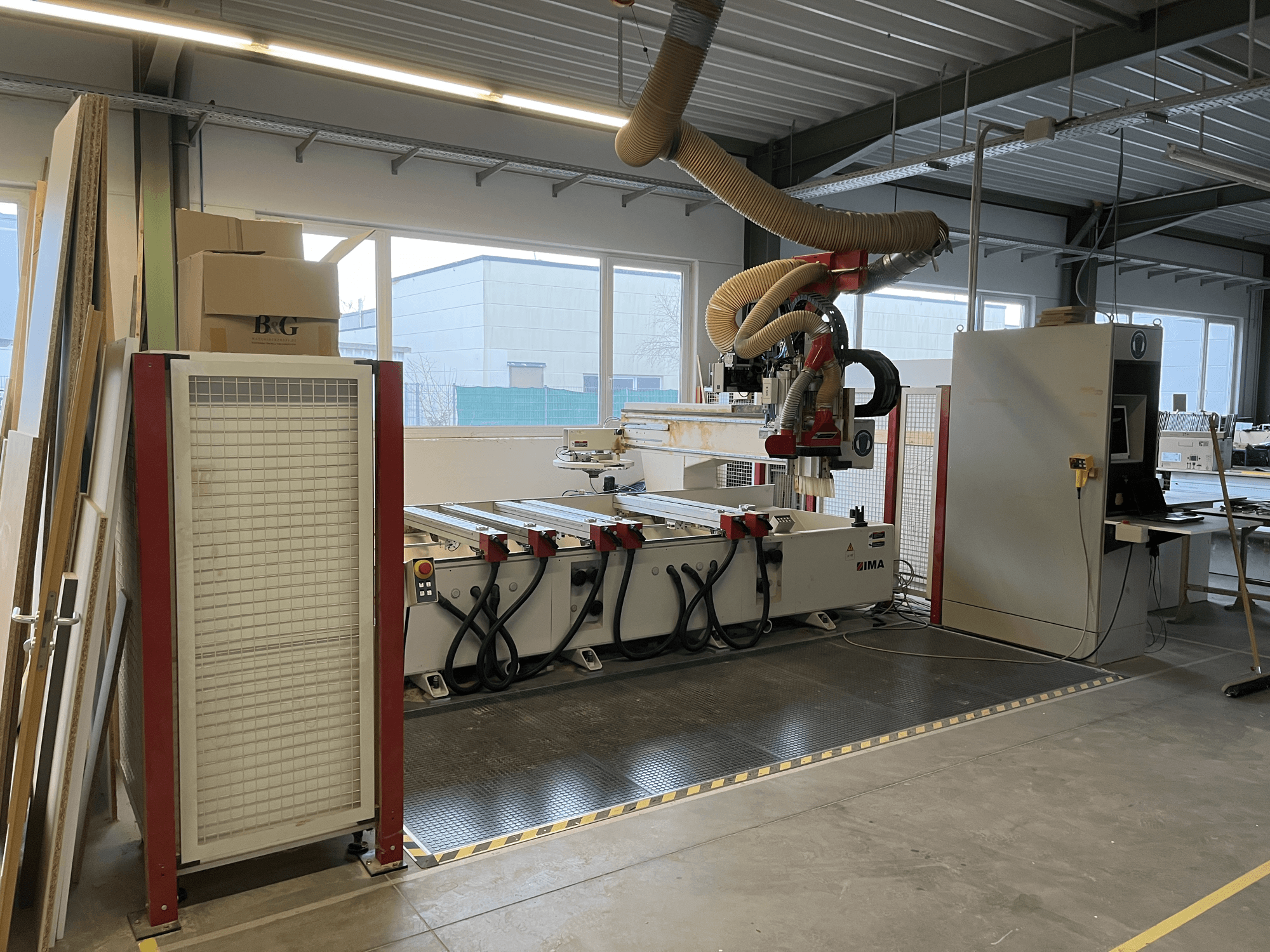 Деревообробний центр з ЧПК IMA BIMA 410 в майстерні, вид збоку з панеллю керування та системою відсмоктування пилу.