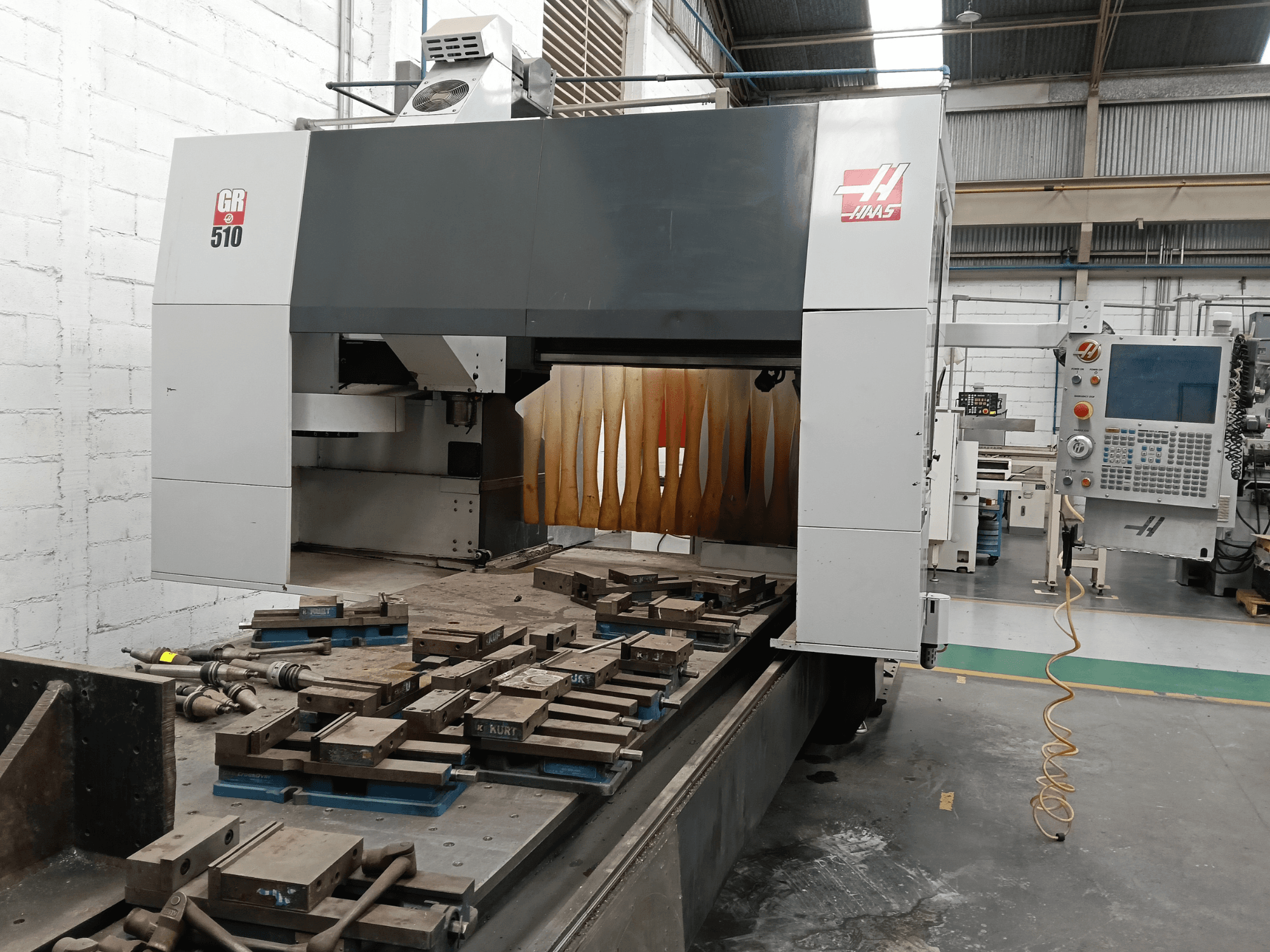 Вигляд спереду портального фрезерного верстата HAAS GR-510, на якому видно панель управління та оброблені деталі на столі.