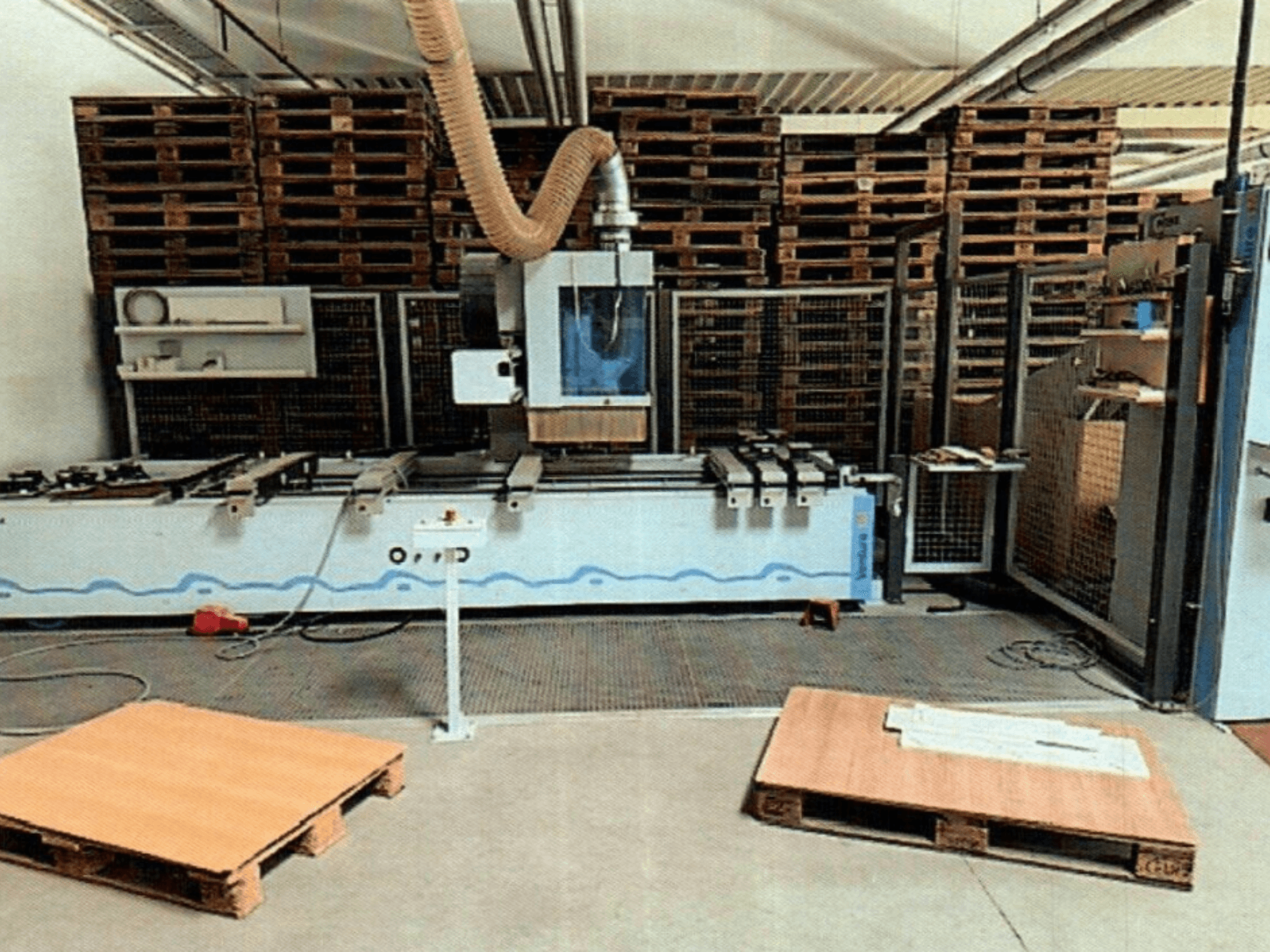 Деревообробний центр з ЧПК Weeke Venture 1M в майстерні, вид спереду з дерев'яними палетами і промисловою установкою.