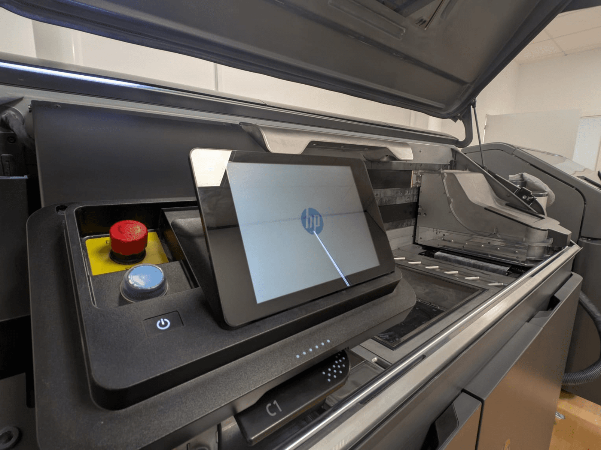 Панель керування принтером HP з планшетним дисплеєм, червоними і синіми кнопками та видом збоку на внутрішні компоненти принтера.