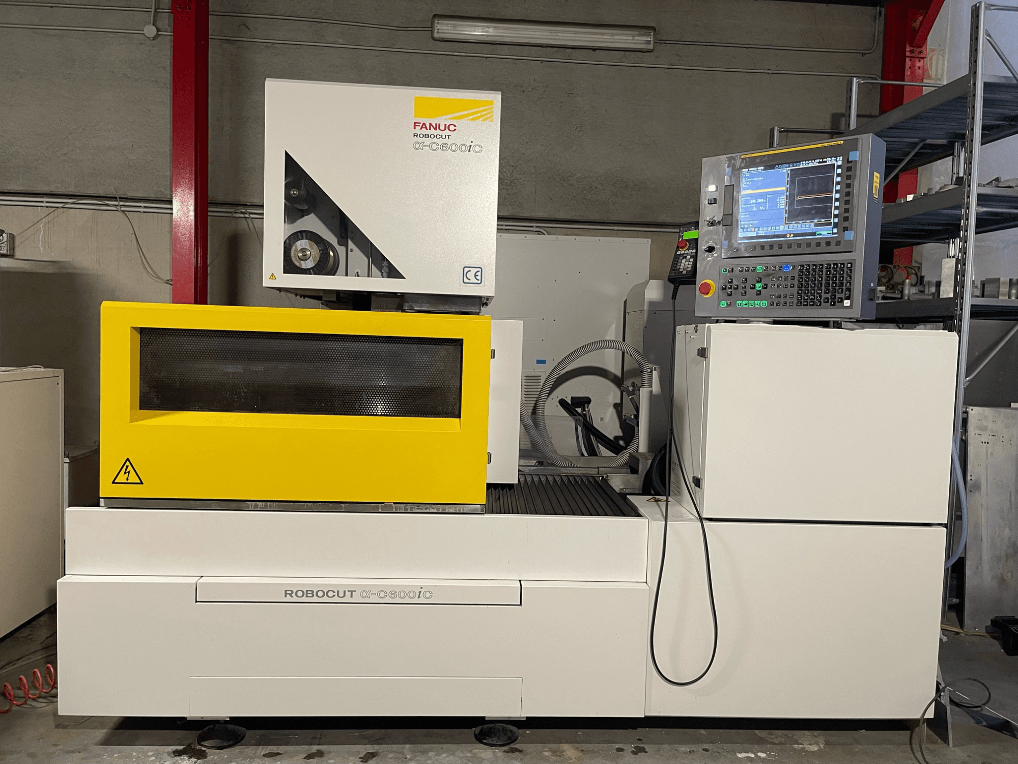 FANUC Robocut α-C600iC, вигляд збоку верстата з ЧПК із жовтим захисним кожухом і панеллю керування, що демонструє можливості точного різання.