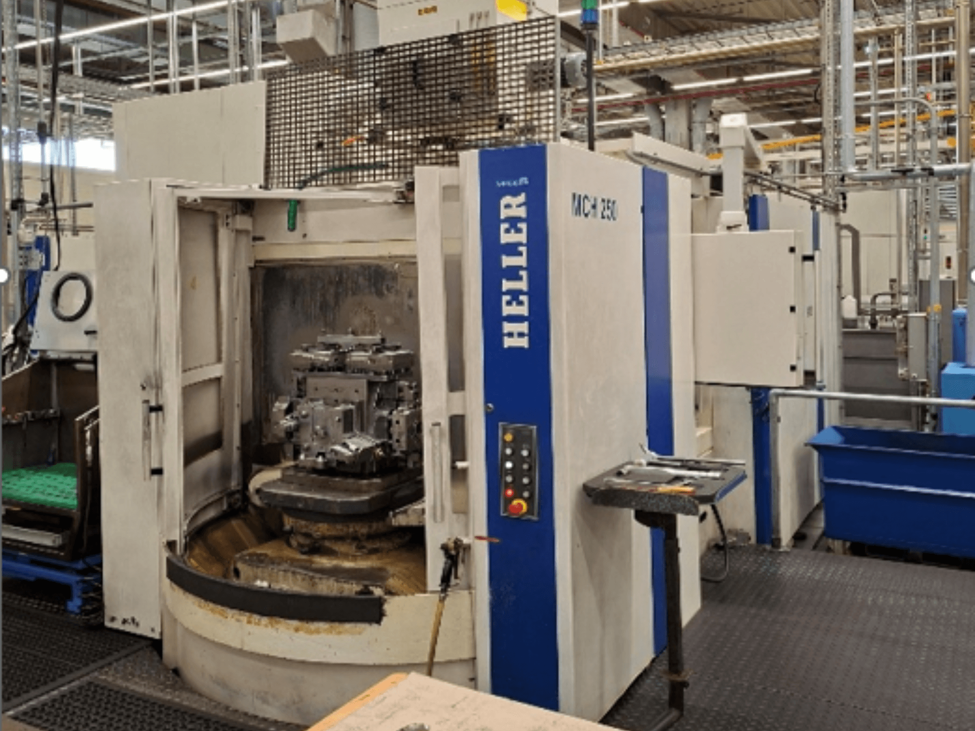 Горизонтальний обробний центр HELLER MCH 250, вид спереду, з відкритими дверцятами, за якими видно заготовку, також видно панель управління.
