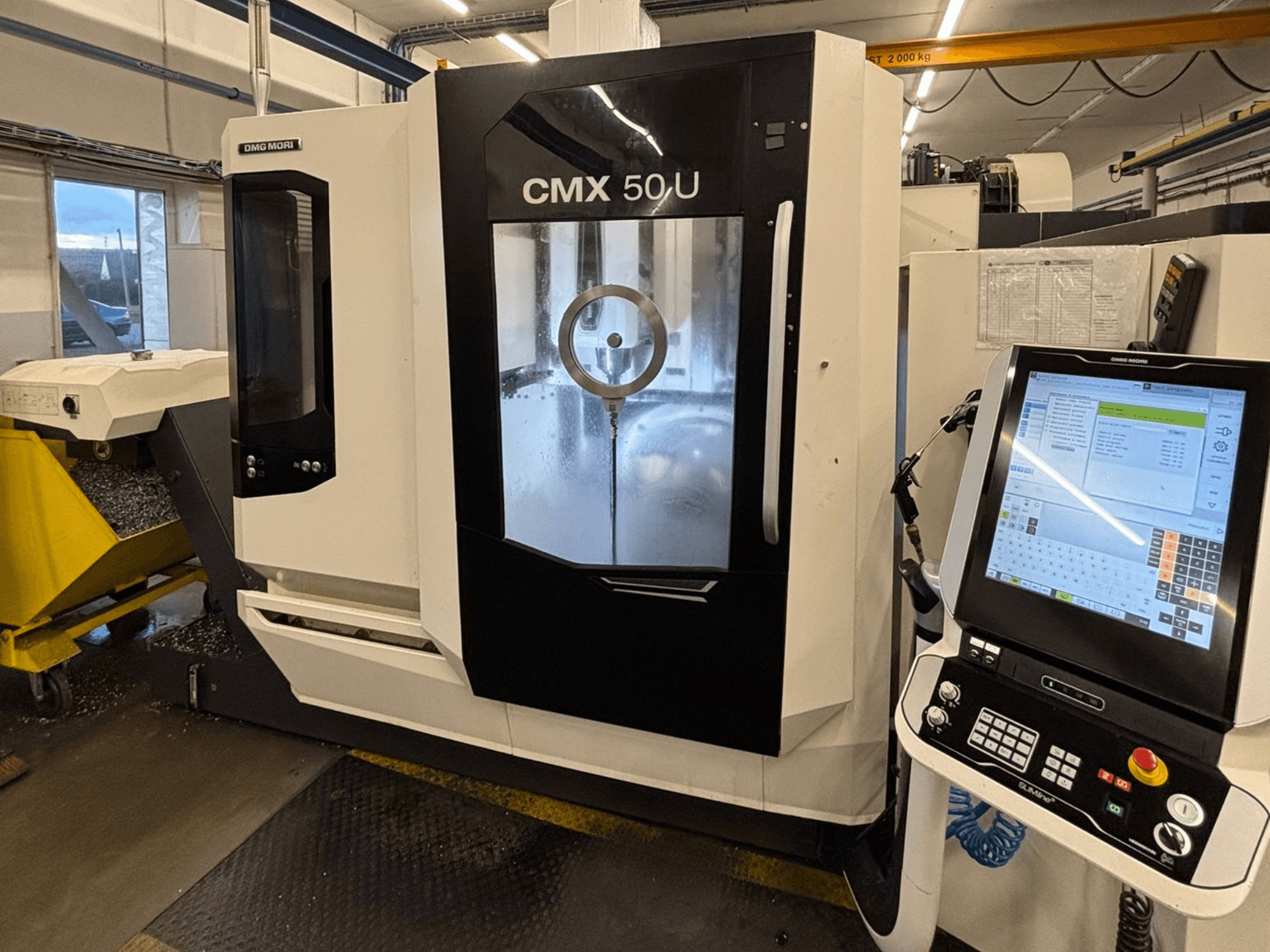 Вертикальний обробний центр DMG MORI CMX 50 U, вид спереду з панеллю керування та скляним дисплеєм, що демонструє внутрішню механіку.