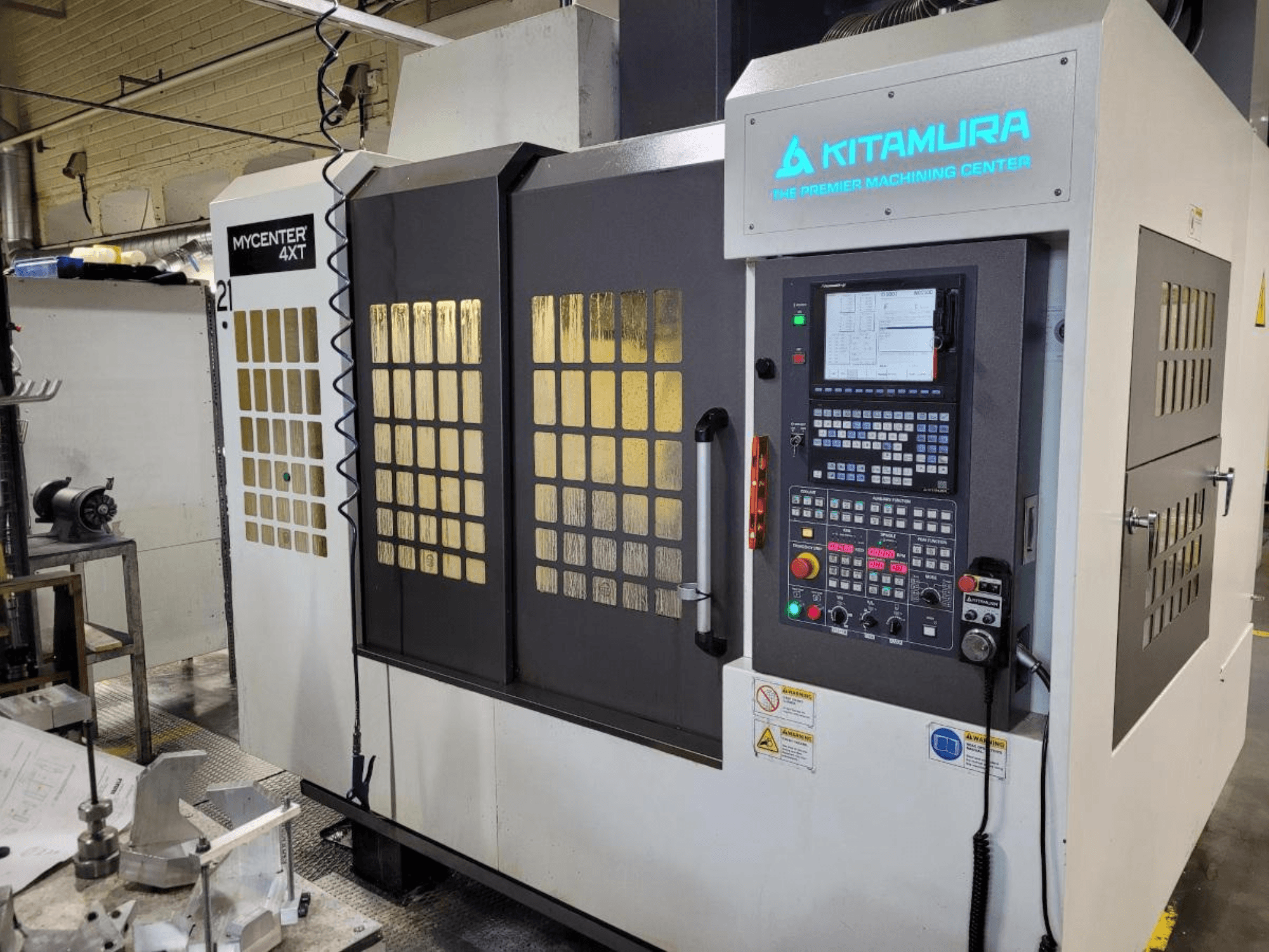 Вертикальний вигляд обробного центру Kitamura Mycenter-4XT з панеллю керування та підсвіченим брендингом.