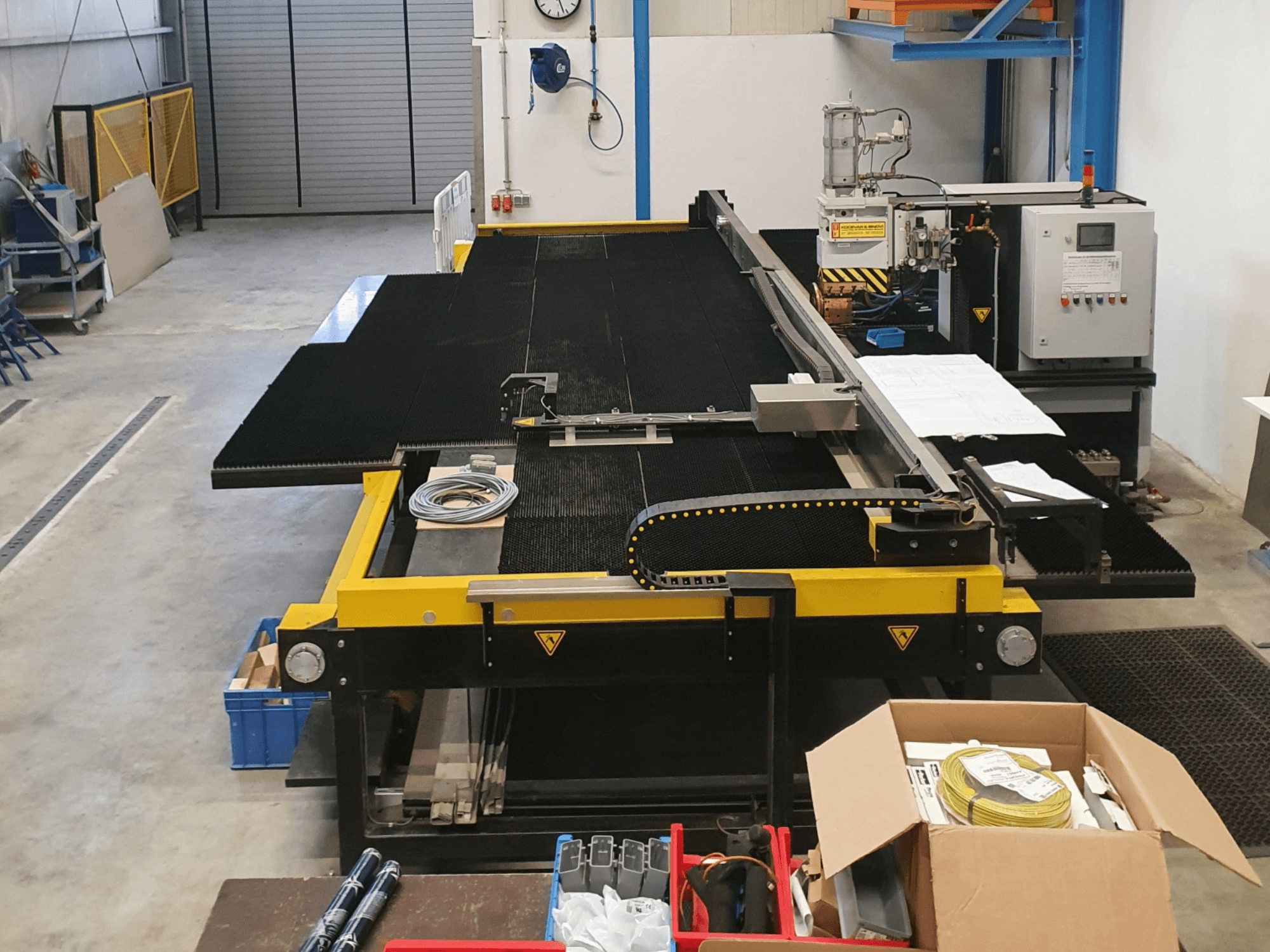 Промисловий розкрійний верстат з жовто-чорними елементами, вид спереду, з елементами керування та аксесуарами у заводському виконанні.