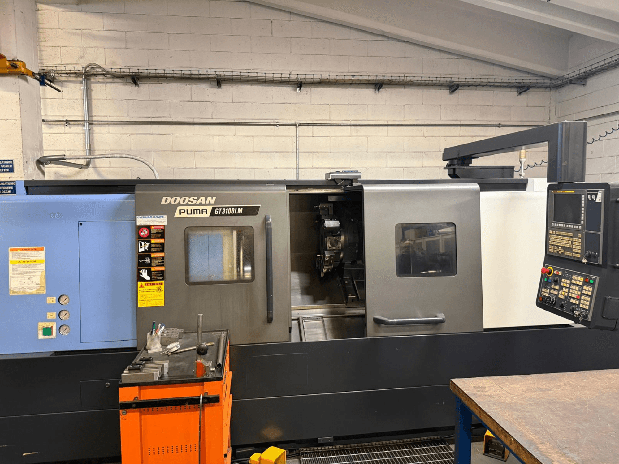 Вид спереду горизонтального токарного верстата DOOSAN PUMA GT3100LM, що демонструє панель керування та робочу зону з інструментами.