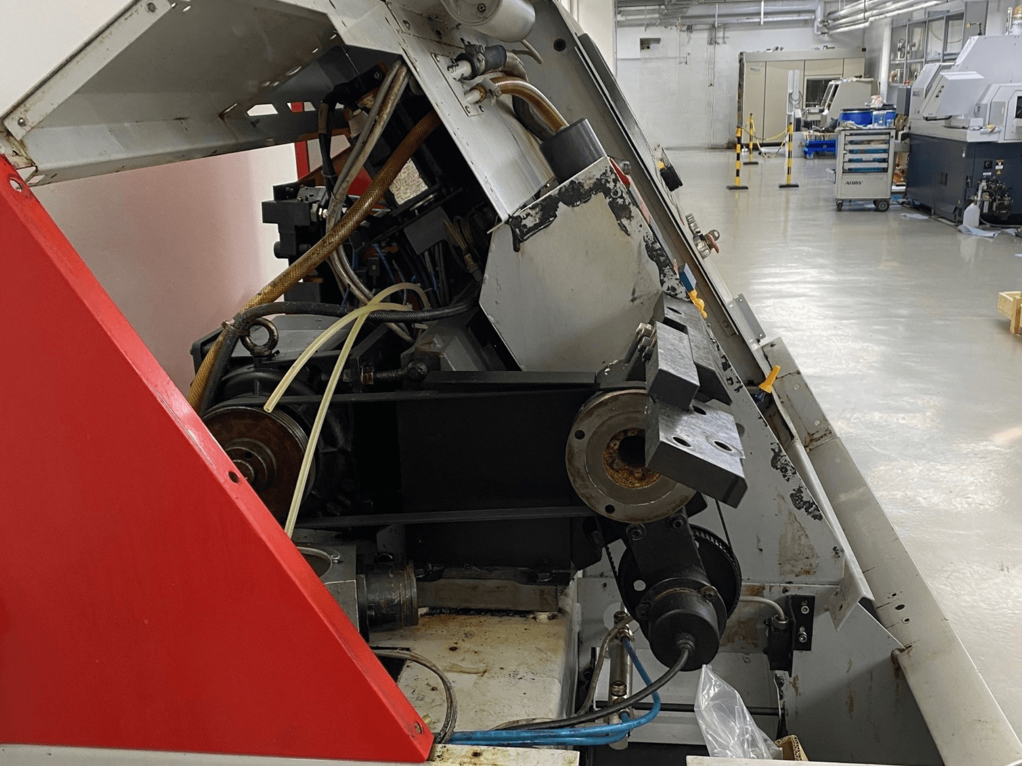 Горизонтальний токарний верстат EMCO Emcoturn 325, вид збоку, де показані компоненти приводу і гідравліки в промислових умовах.