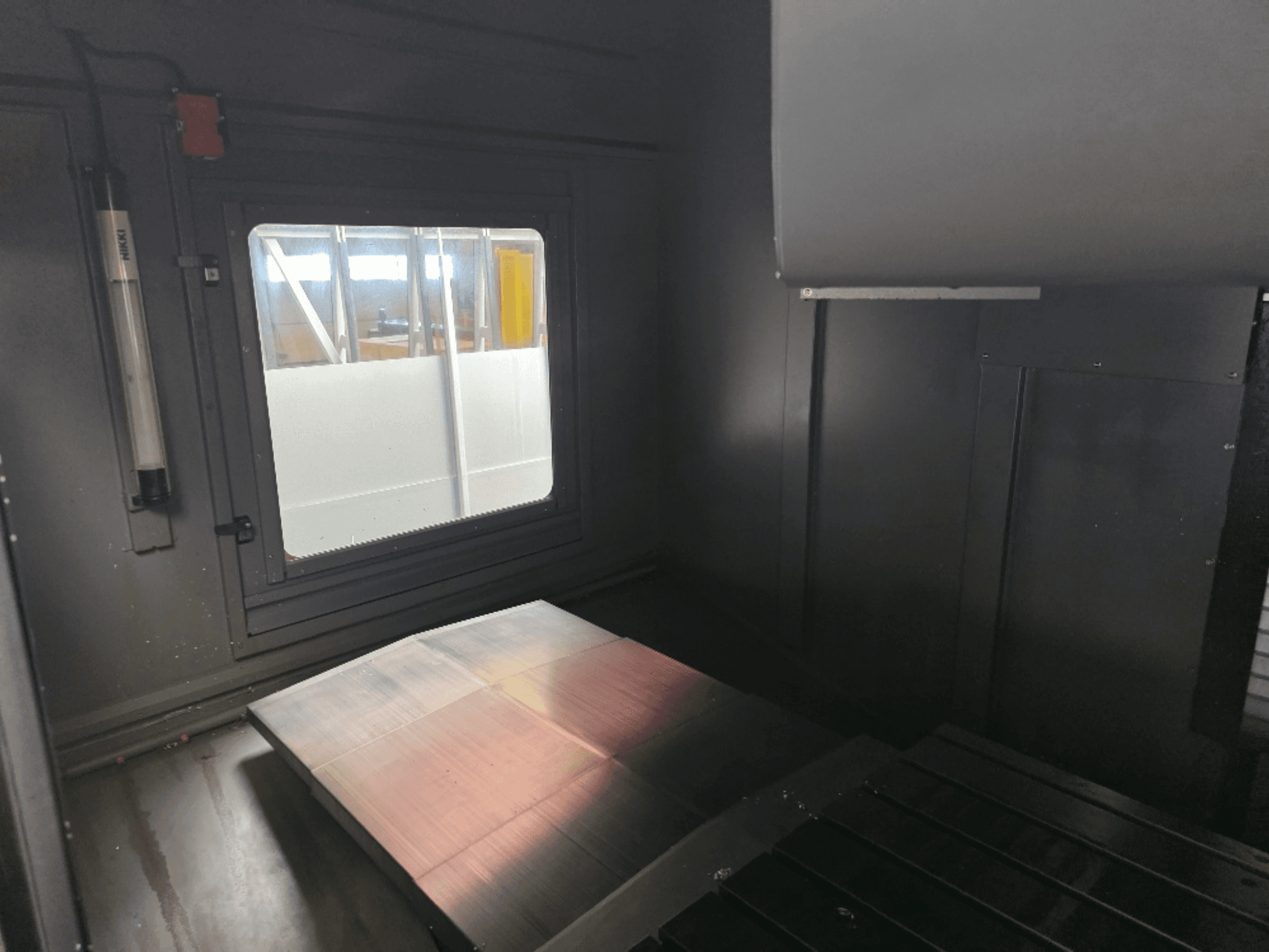 Внутрішній вигляд корпусу машини з полірованою металевою пластиною, бічним вікном і мінімальним освітленням. Бренд не видно.