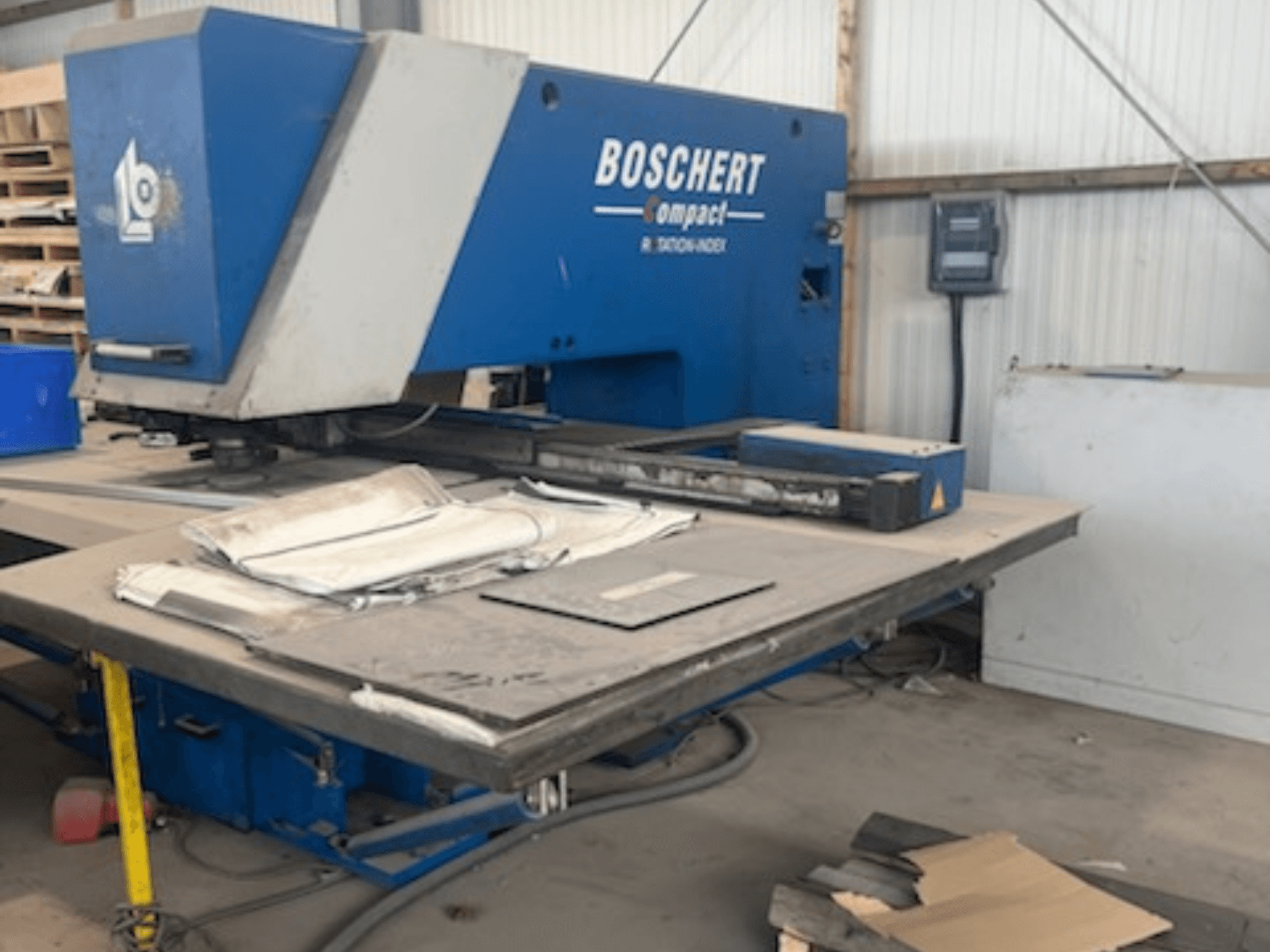Штампувальний верстат з ЧПУ BOSCHERT COMPACT 1000 у цеху; на фото показано фасад верстата з металевими листами на столі.