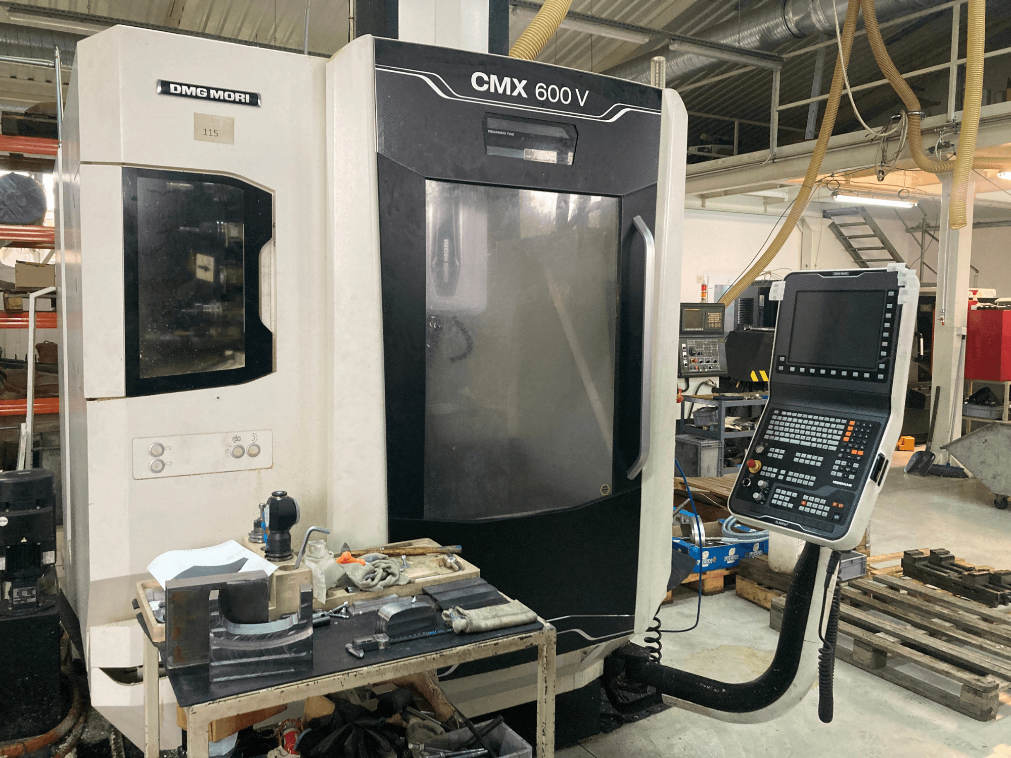 Фрезерний верстат DMG MORI CMX 600 V спереду, з панеллю керування та робочим столом з інструментами.