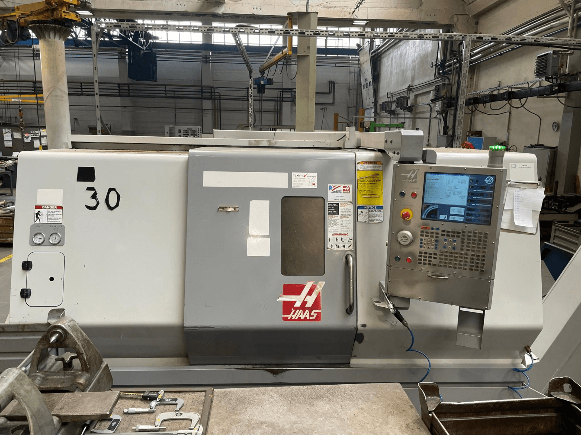 Горизонтальний токарний верстат Haas SL-30THE у фронтальному ракурсі, на якому видно цифрову панель управління, попереджувальні наклейки та номер моделі 30.
