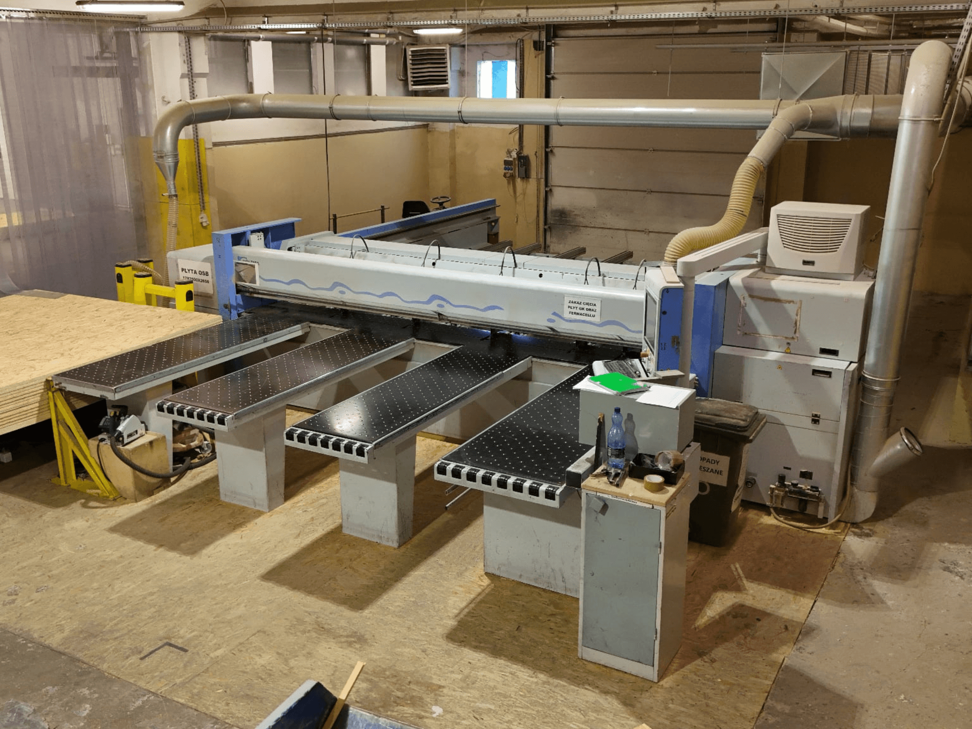 Панельний пильний верстат HOLZMA HPP 350/43/38 у цеху, вид зверху, на якому видно зону різання та опорні столи.