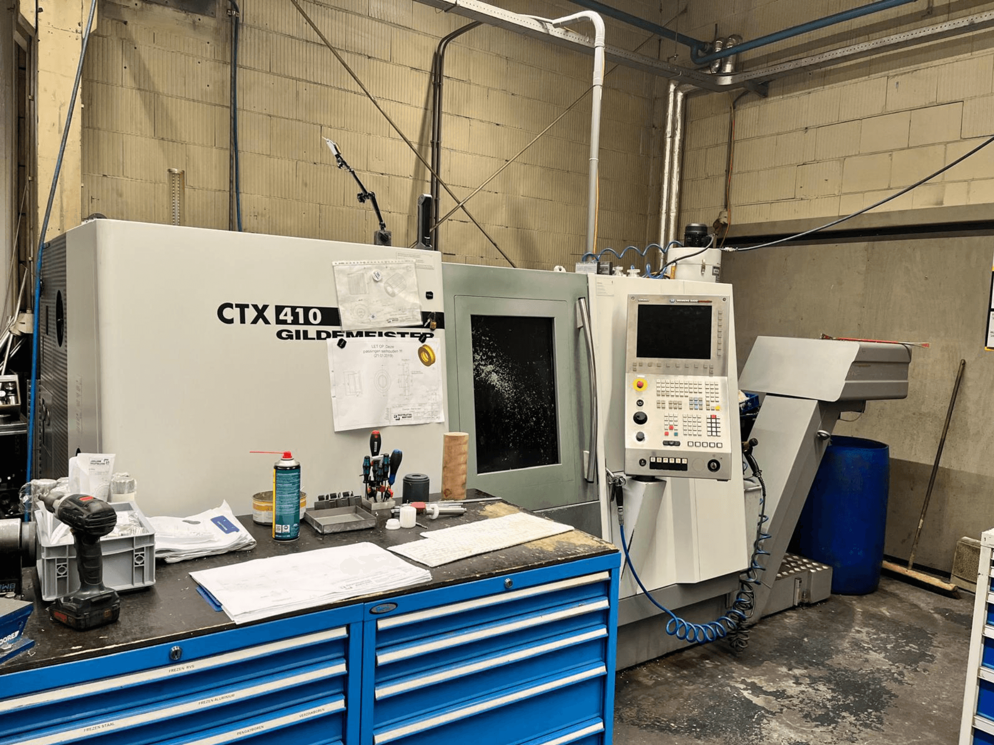 Верстат з ЧПК Gildemeister CTX 410 в майстерні, вид спереду, з панеллю керування та різними інструментами на робочому столі.