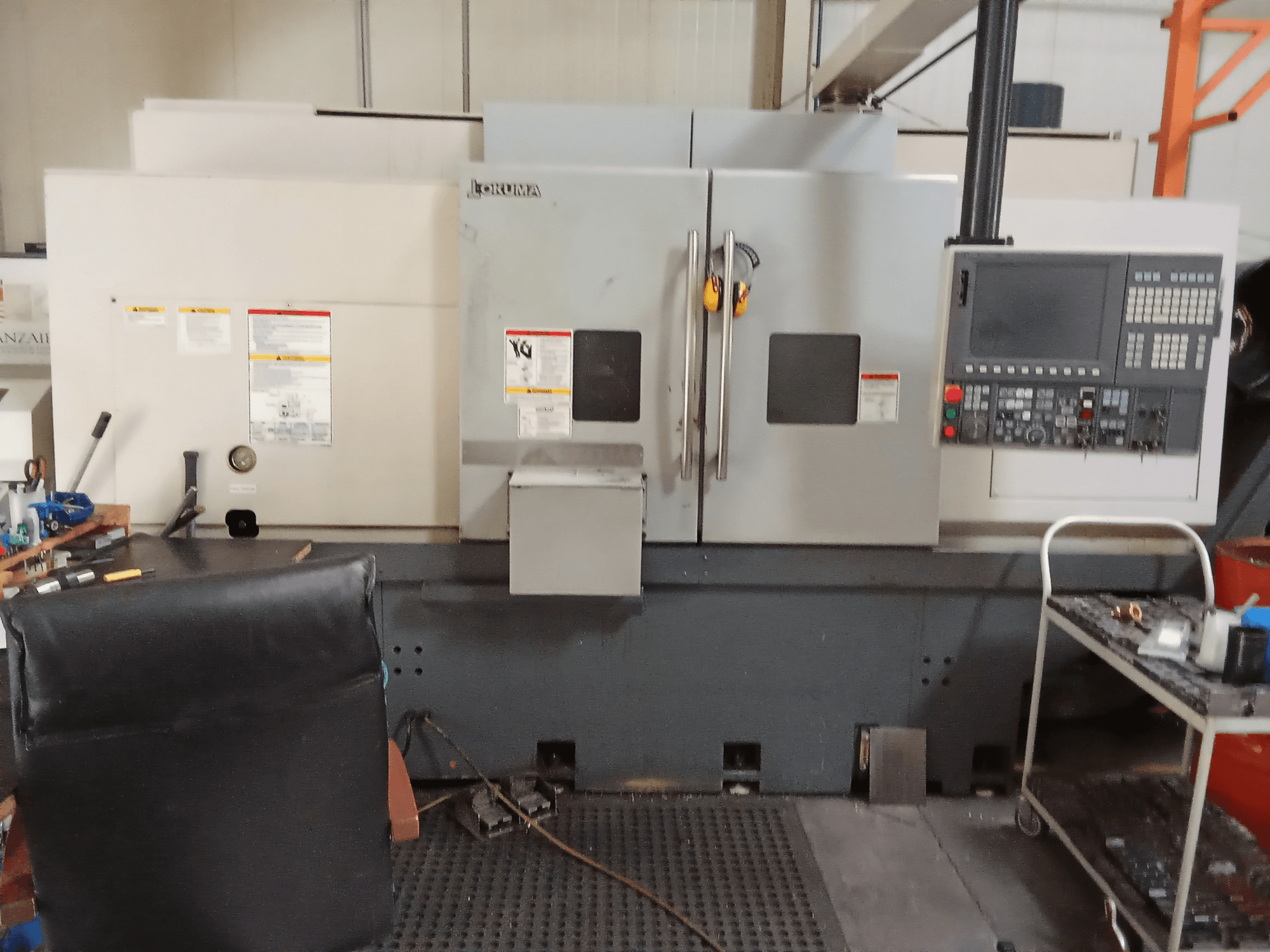 Горизонтальний токарний верстат Okuma Genos L300 E-M, вид спереду, демонструє панель керування та подвійні двері, встановлений в умовах майстерні.