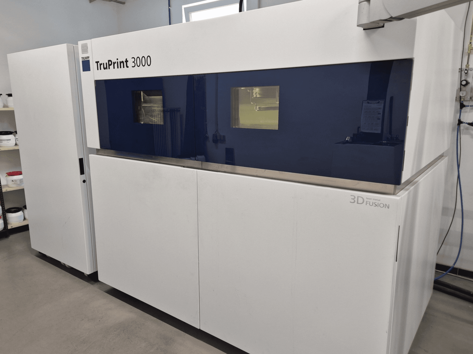 Металевий 3D-принтер TruPrint 3000 спереду, з блакитними панелями та технологією лазерного зварювання.