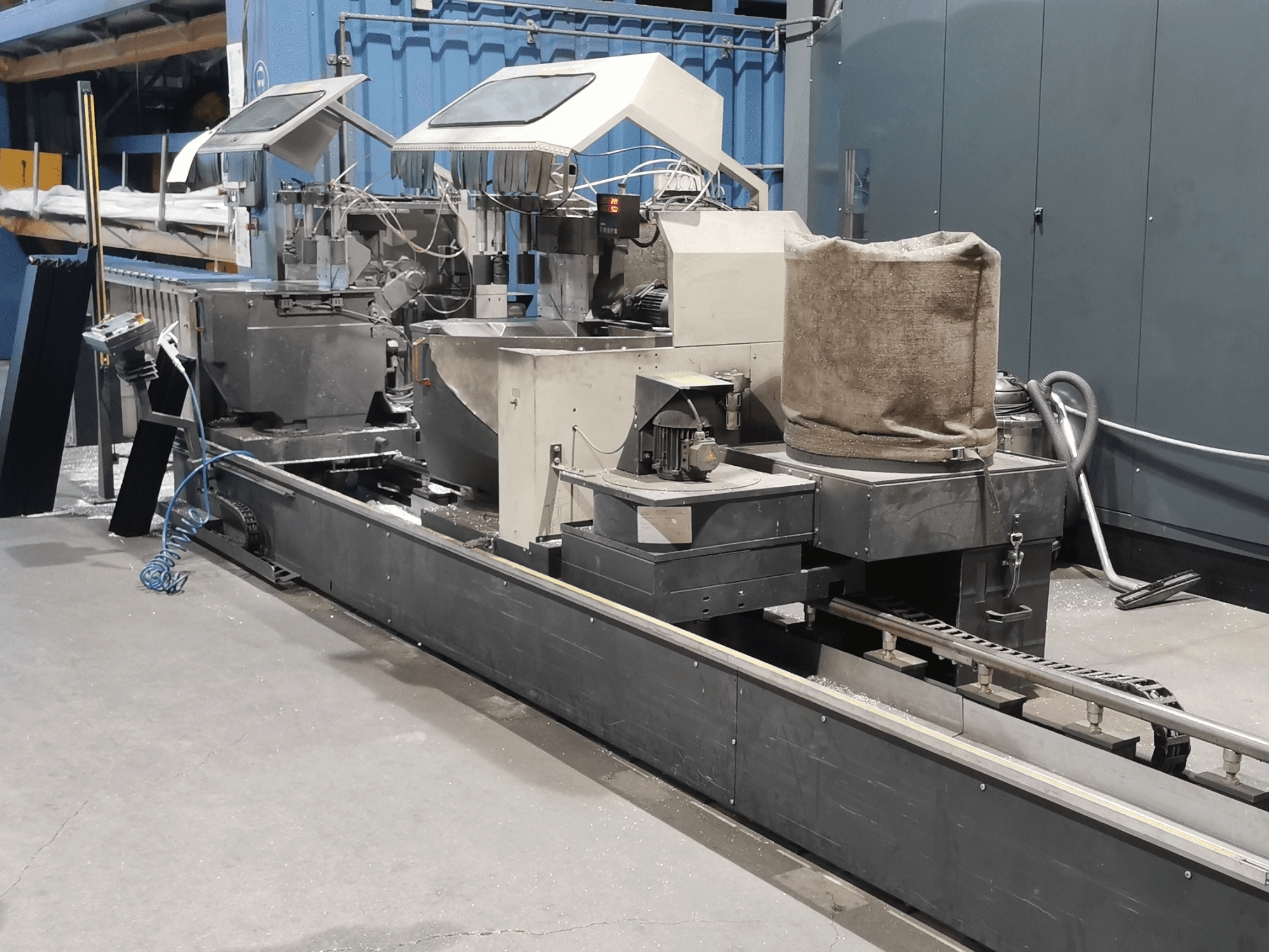 Промислова переробна машина, вид збоку, з бункерами, конвеєрною стрічкою та панеллю керування, в заводських умовах.