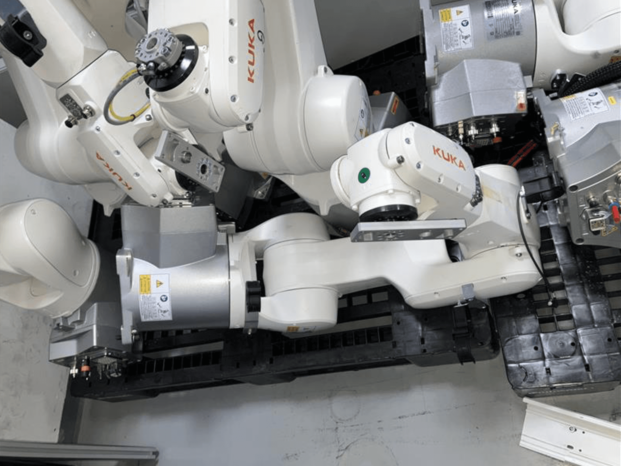 Робот-маніпулятор KUKA KR 6 R900 CR у вигляді зверху, з численними шарнірами та двигунами, встановлений на чорній основі з кабелями.