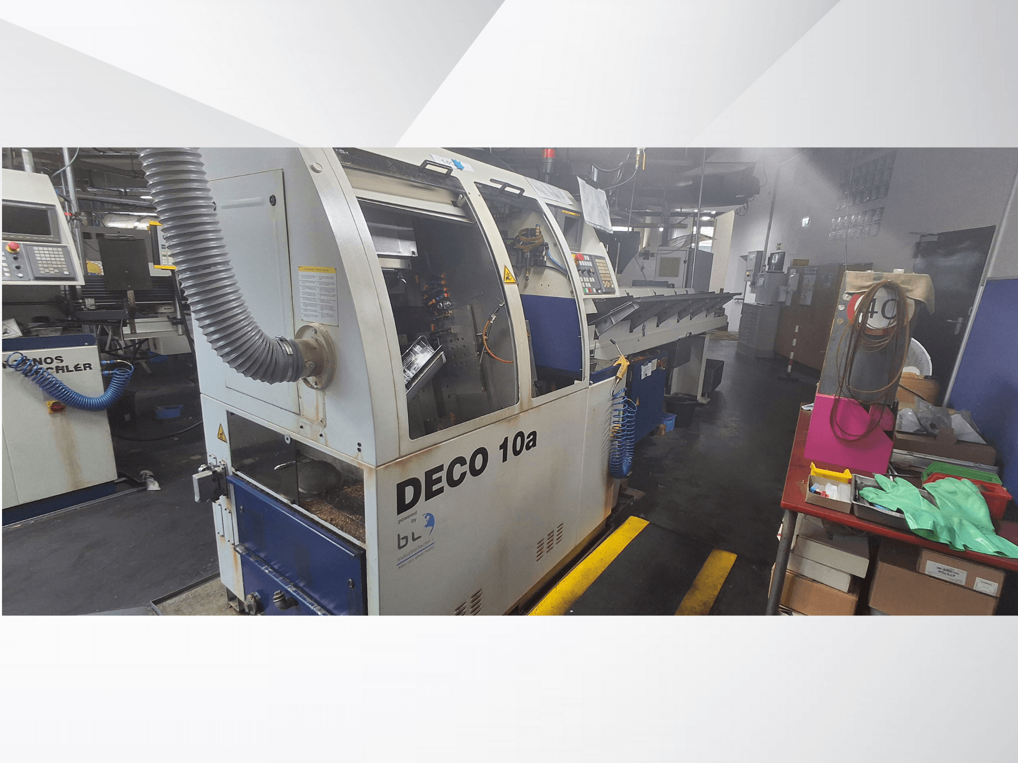 Верстат з ЧПК DECO 10a в майстерні, вид спереду; оснащений панеллю керування та системою відсмоктування пилу, поруч стоїть робочий стіл.