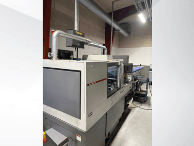 Промислове обладнання від бренду MVC, вид збоку з панеллю керування та повітропроводами, встановлене в заводських умовах.