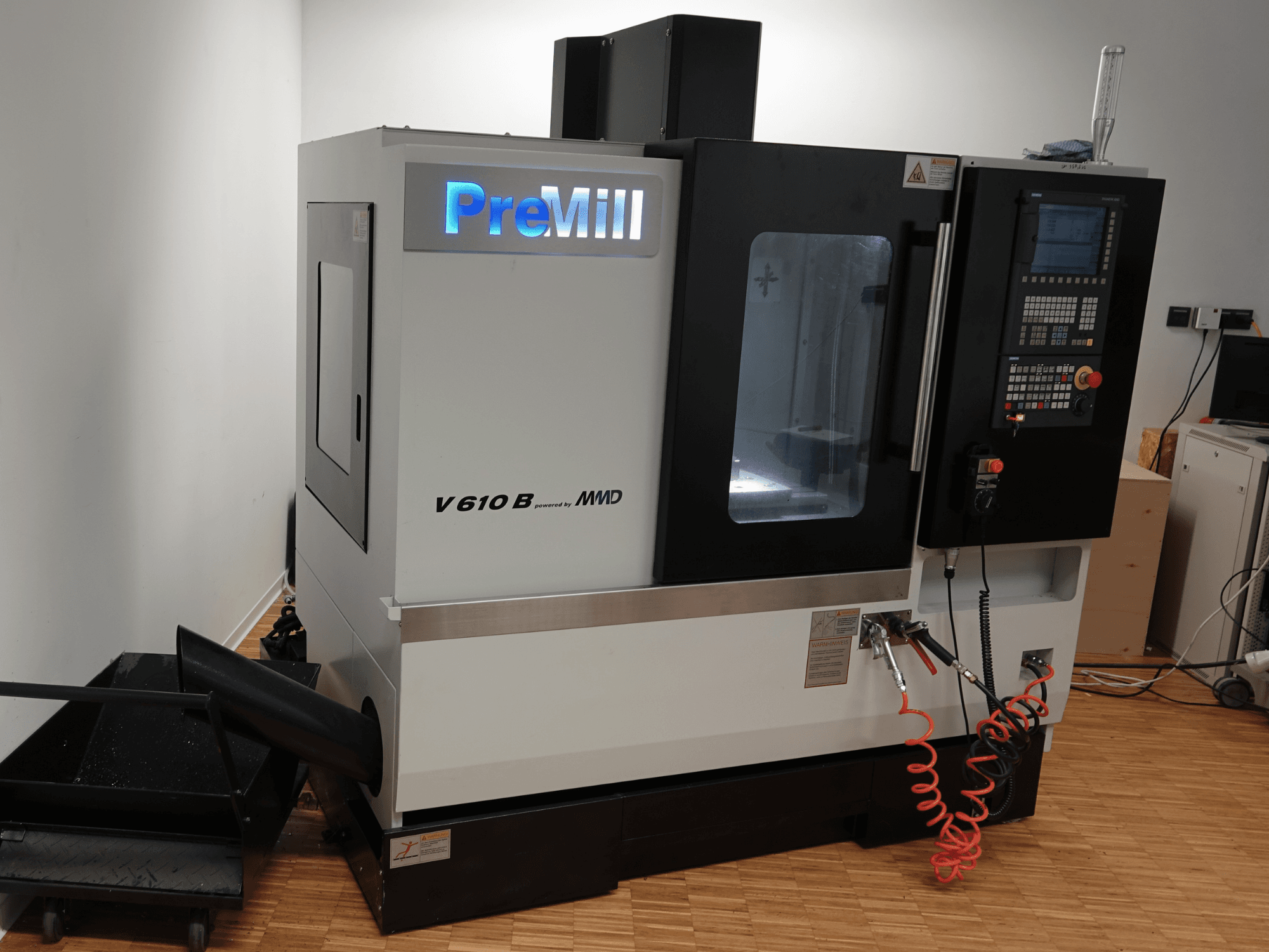 Вертикальний обробний центр PreMill V 610 B, вид спереду, з панеллю управління, системою охолодження та підключеними повітряними шлангами.