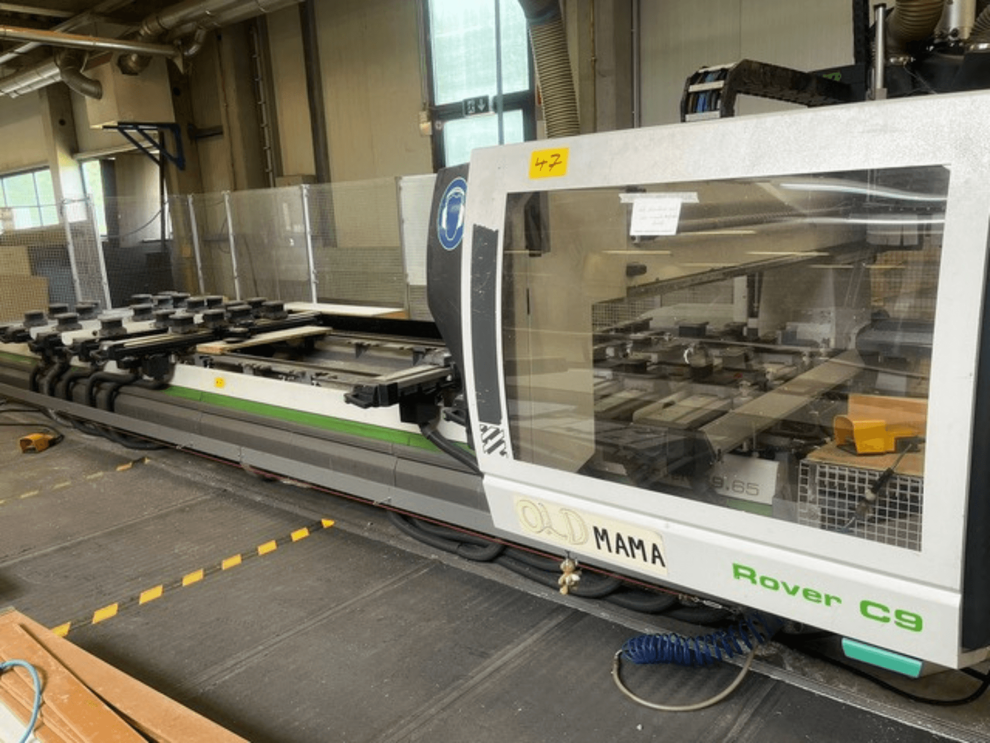 Фрезерний верстат з ЧПК BIESSE Rover C 9.65 в майстерні, вид збоку: панель керування та робочий стіл із затискачами.