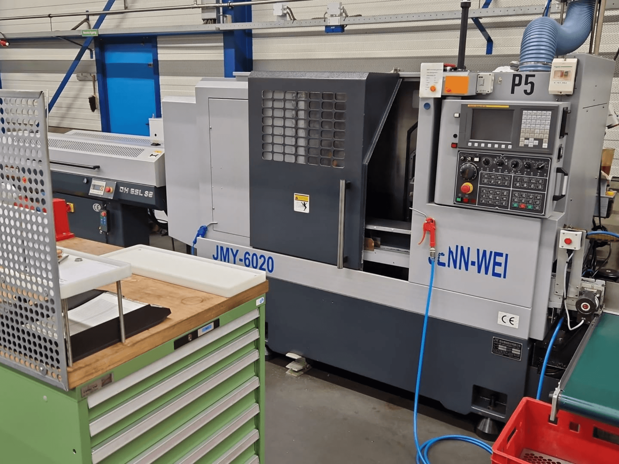 Токарний верстат з ЧПУ, модель JMY-6020 від cNN-WEI, вид спереду. Має панель керування, аварійну зупинку та лінію подачі охолоджувальної рідини.