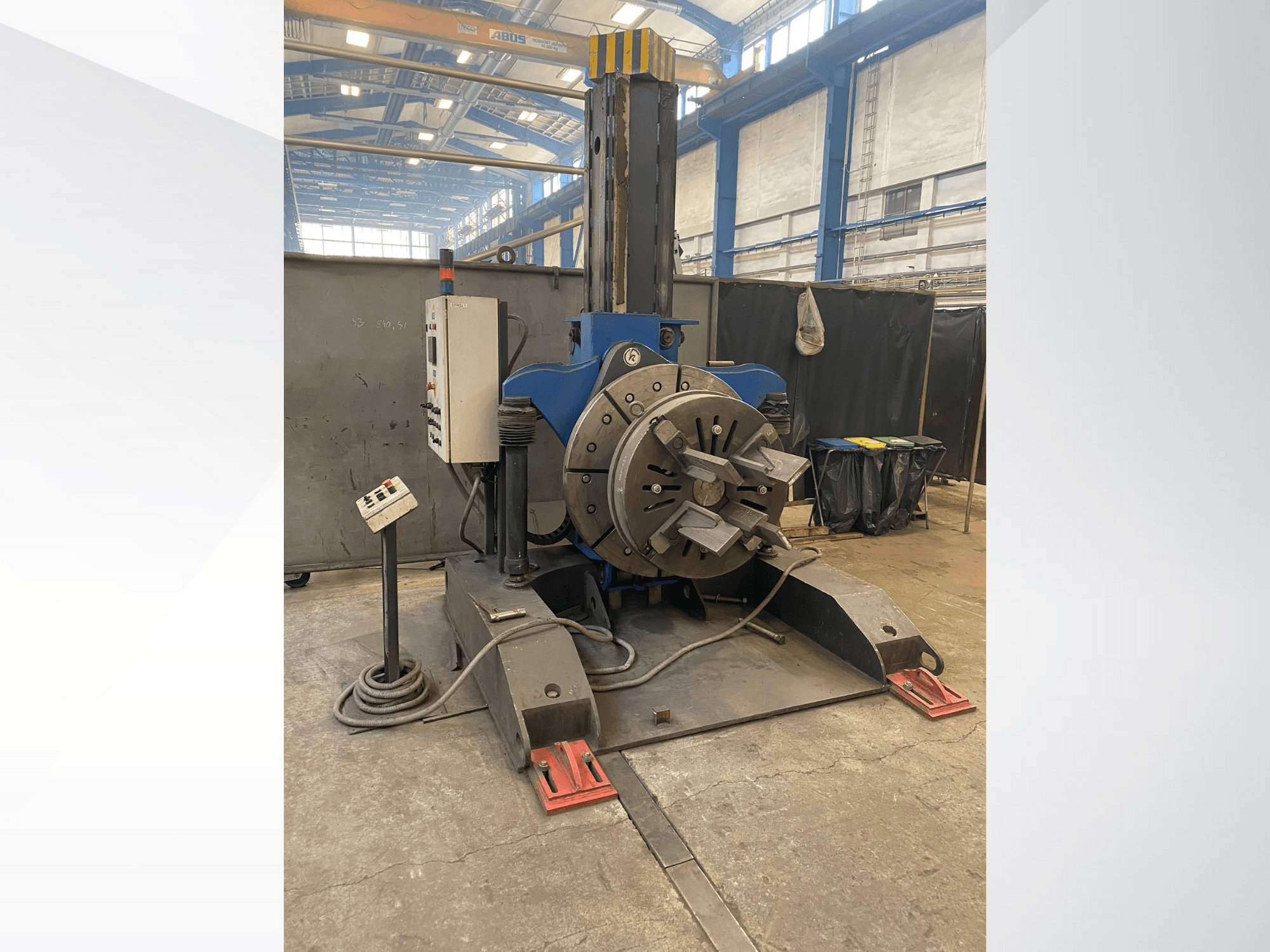 Синій промисловий токарний верстат з круглою поворотною головкою і панеллю керування, вид збоку, в умовах майстерні.