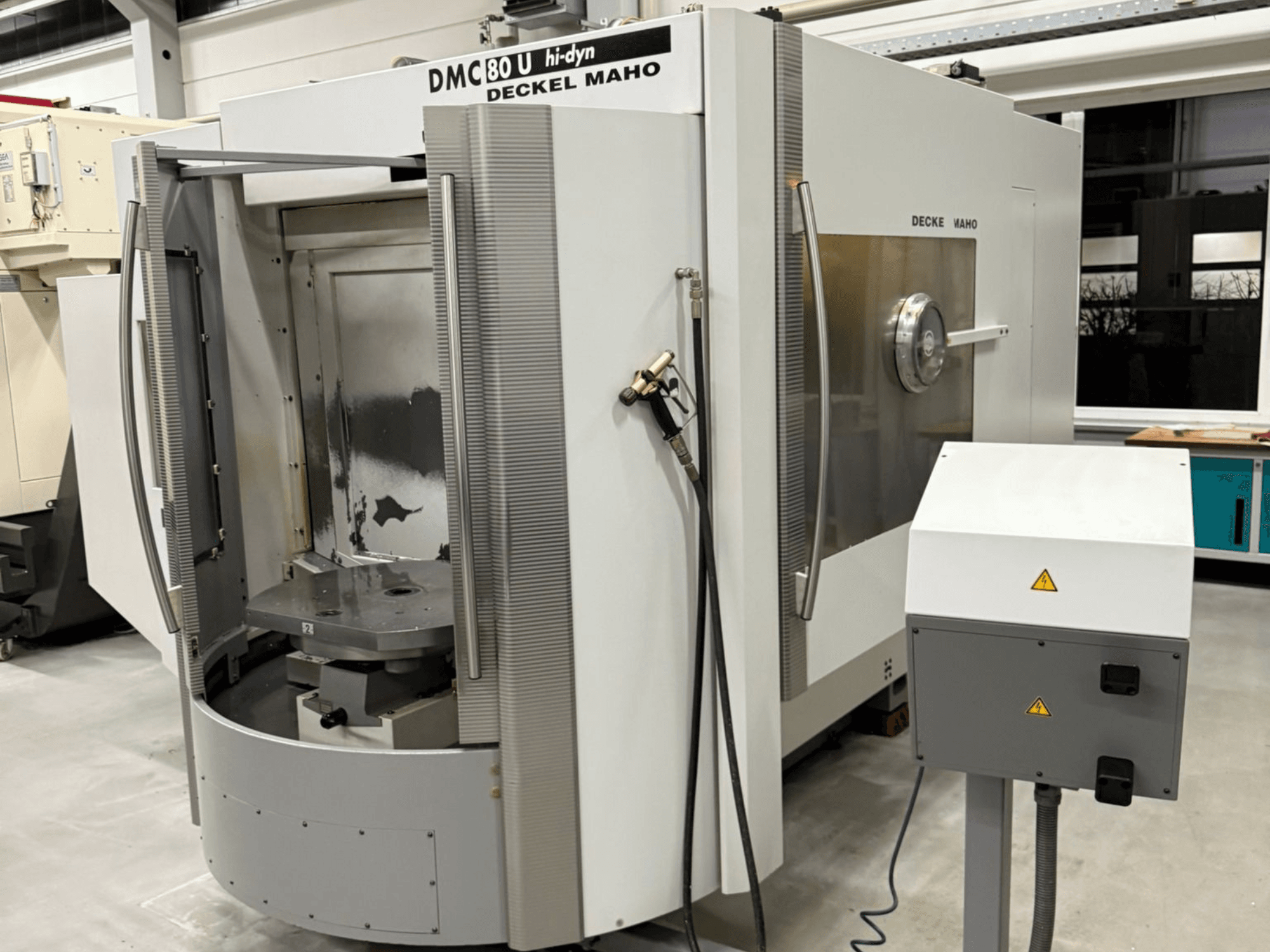 Вид спереду високошвидкісного фрезерного верстата з ЧПК Deckel Maho DMC 80 U з відкритими дверцятами доступу та панеллю керування збоку.
