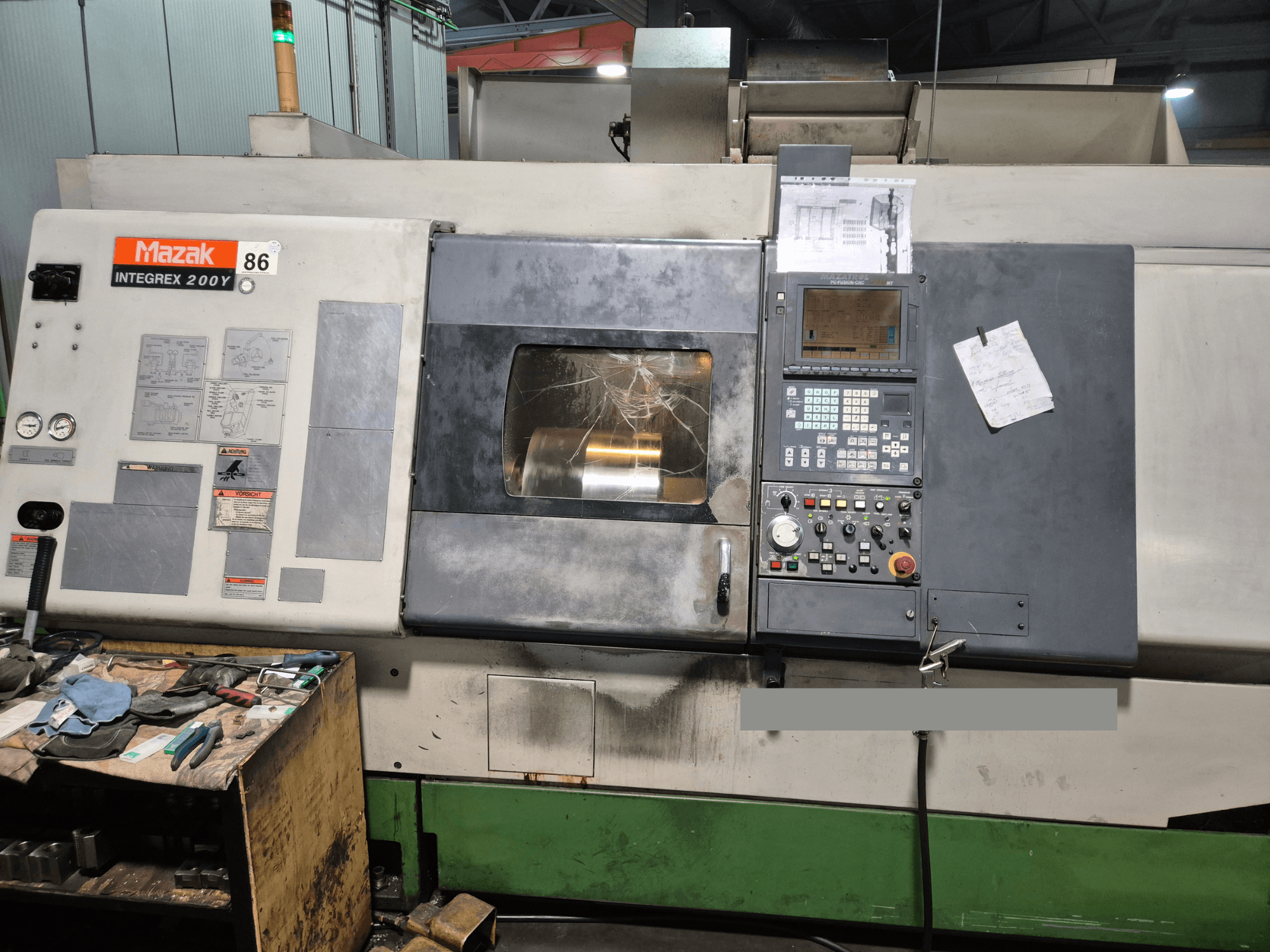 Токарний верстат Mazak Integrex 200Y, вид спереду, з панеллю керування та інструментами на столі. Видимі вимірювальні прилади та екран дисплея.