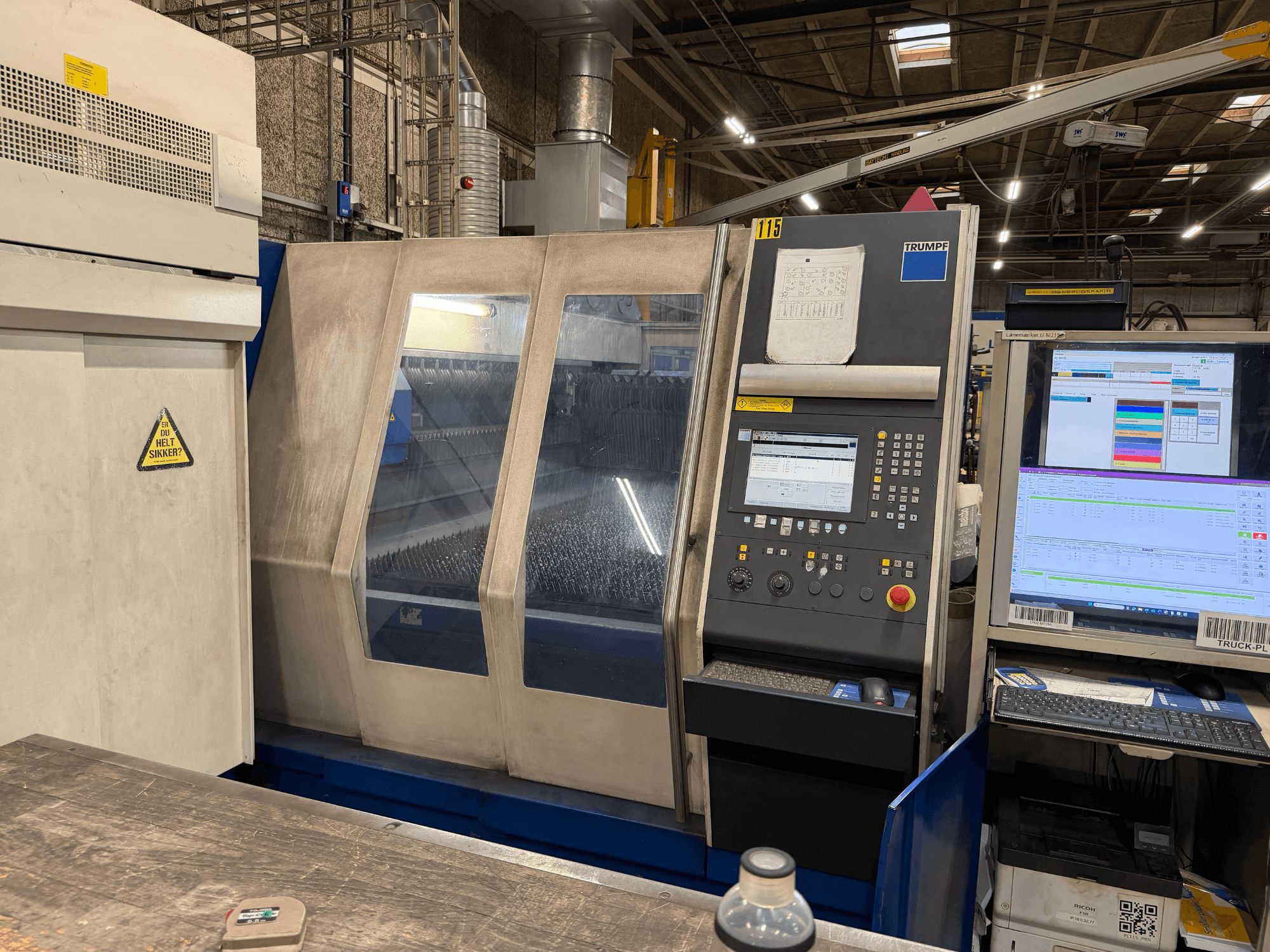 Вид спереду промислового лазерного верстата Trumpf з панеллю керування та цифровими дисплеями, встановленого в заводських умовах.