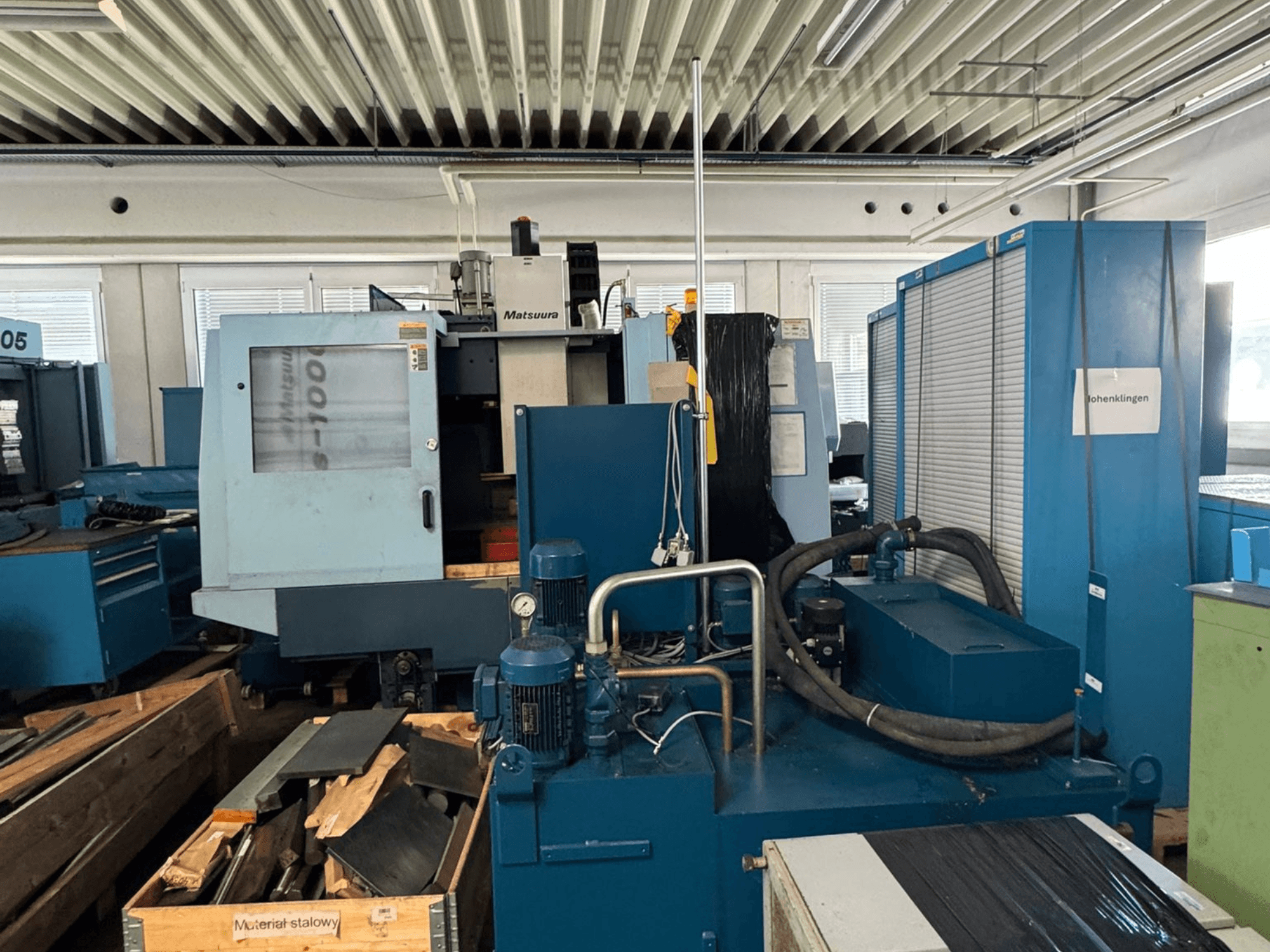 Вигляд спереду вертикального обробного центру Matsuura Vplus 1000/40, на якому видно елементи управління, двигуни та навколишнє робоче середовище.