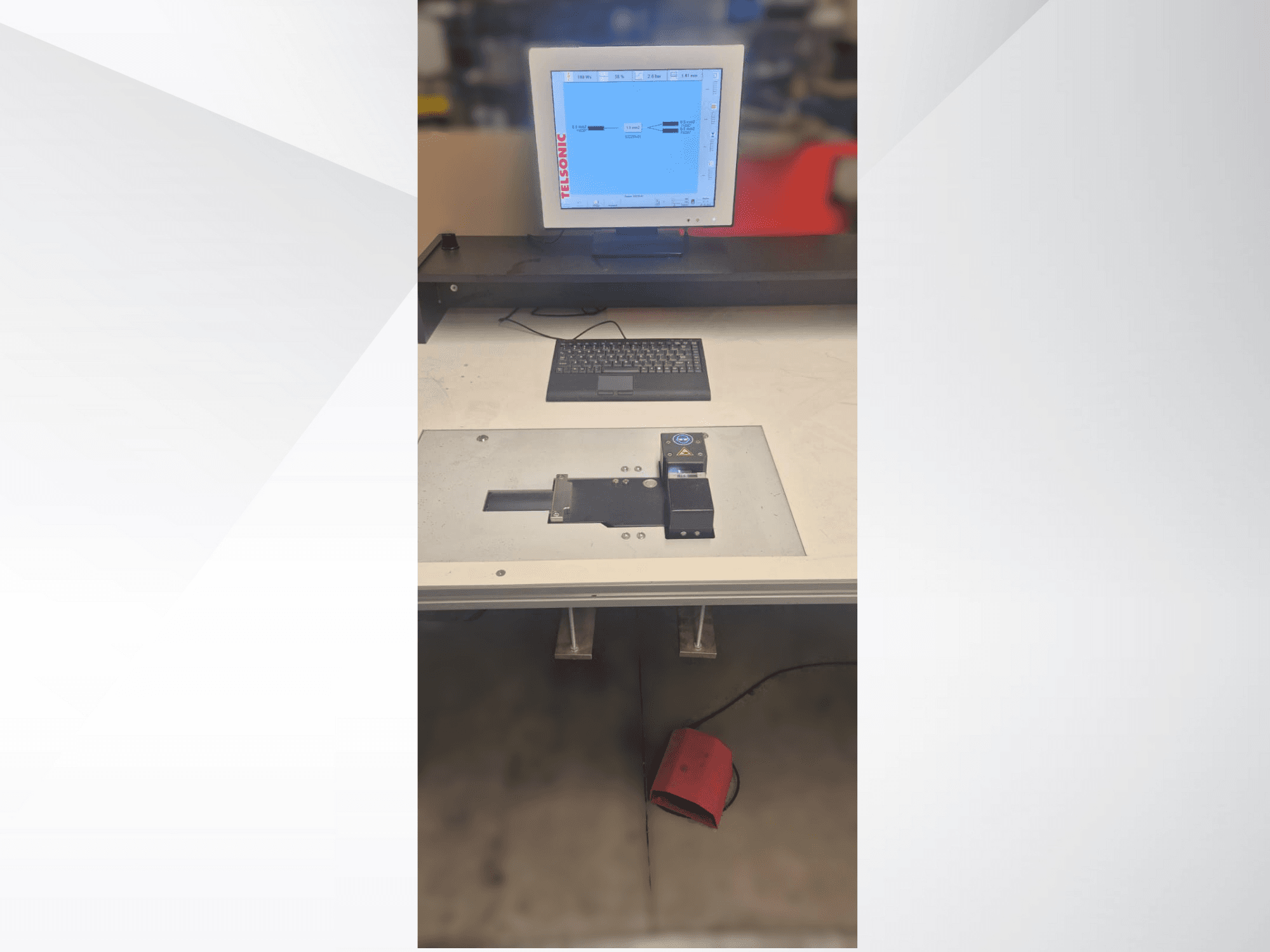 Вид зверху вниз на випробувальну станцію з комп'ютерним монітором, клавіатурою та панеллю керування з кнопкою і зеленим світлом.