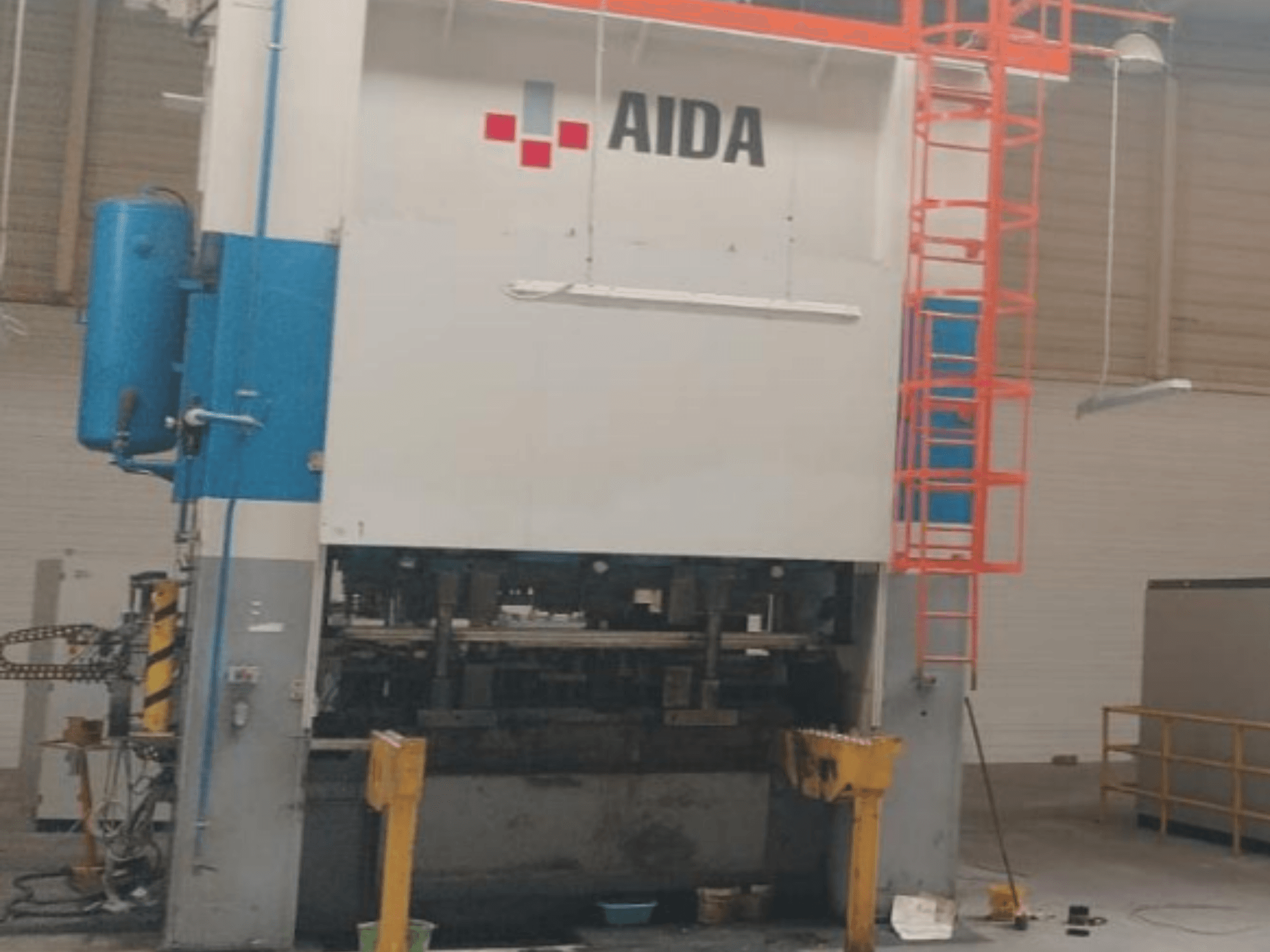 Механічний штампувальний прес AIDA 315/2MR/LD/TE3, вид спереду, демонструє гідравлічні компоненти та захисну драбину.