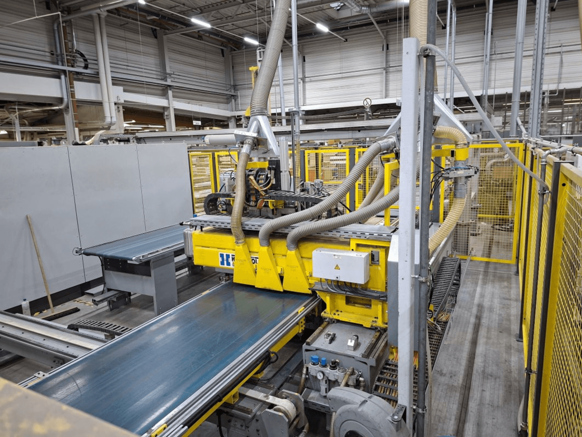 Промислова конвеєрна система збоку, з жовтими механізмами, панеллю керування та шланговими кріпленнями для виробництва.