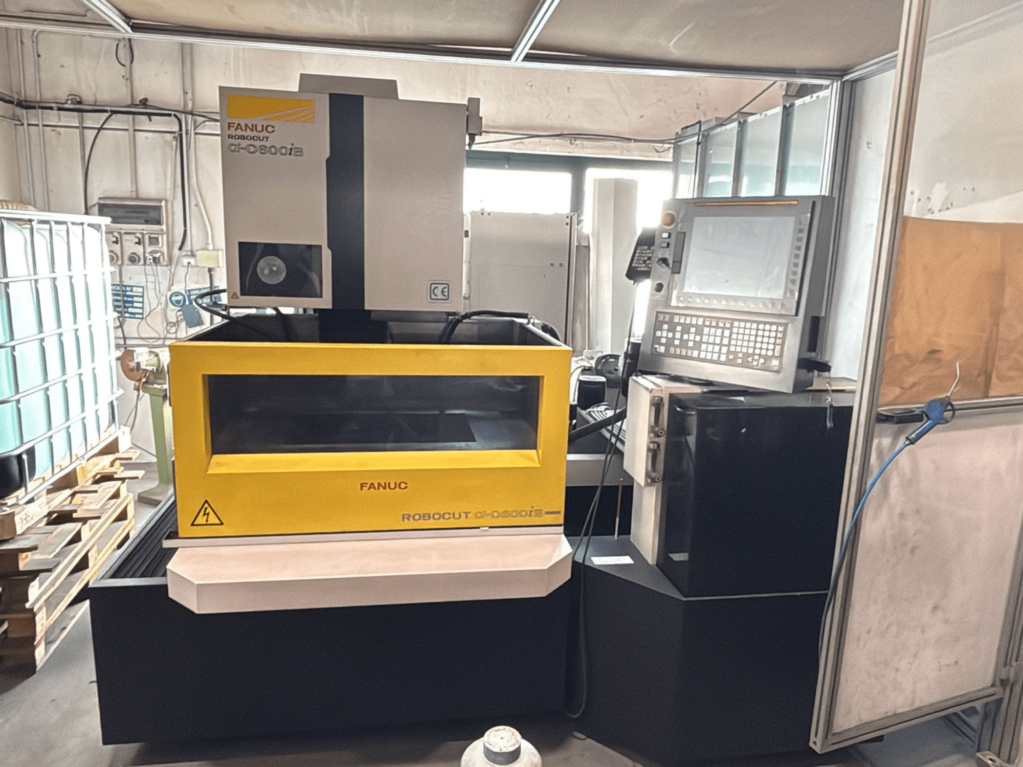 Вид спереду верстата з ЧПК FANUC Robocut α-0iE з жовтим корпусом, що демонструє панель керування та дисплей.
