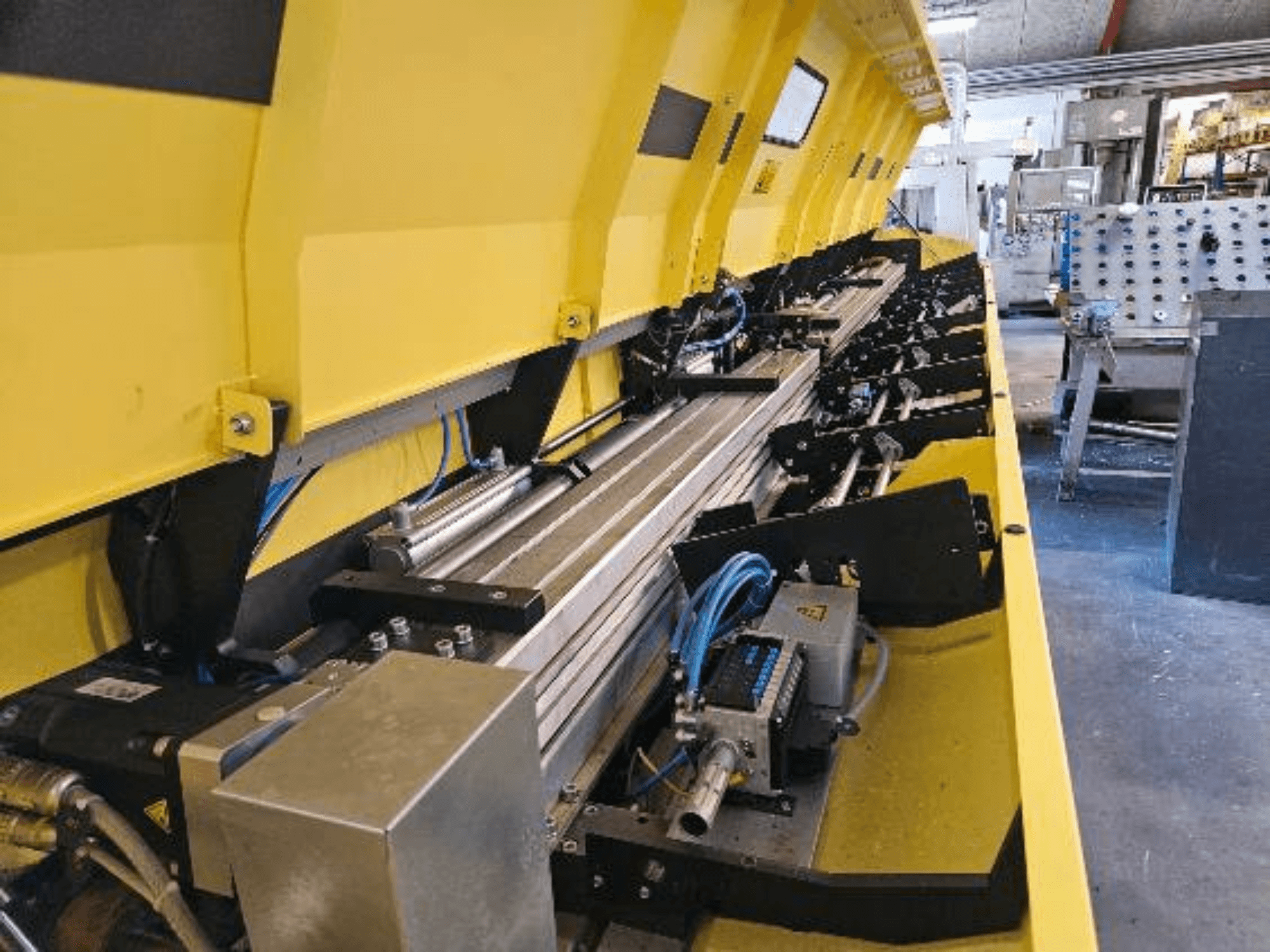 Крупним планом жовта гідравлічна машина з металевими компонентами та конвеєрними доріжками, на яких прокладені шланги та електронні деталі.