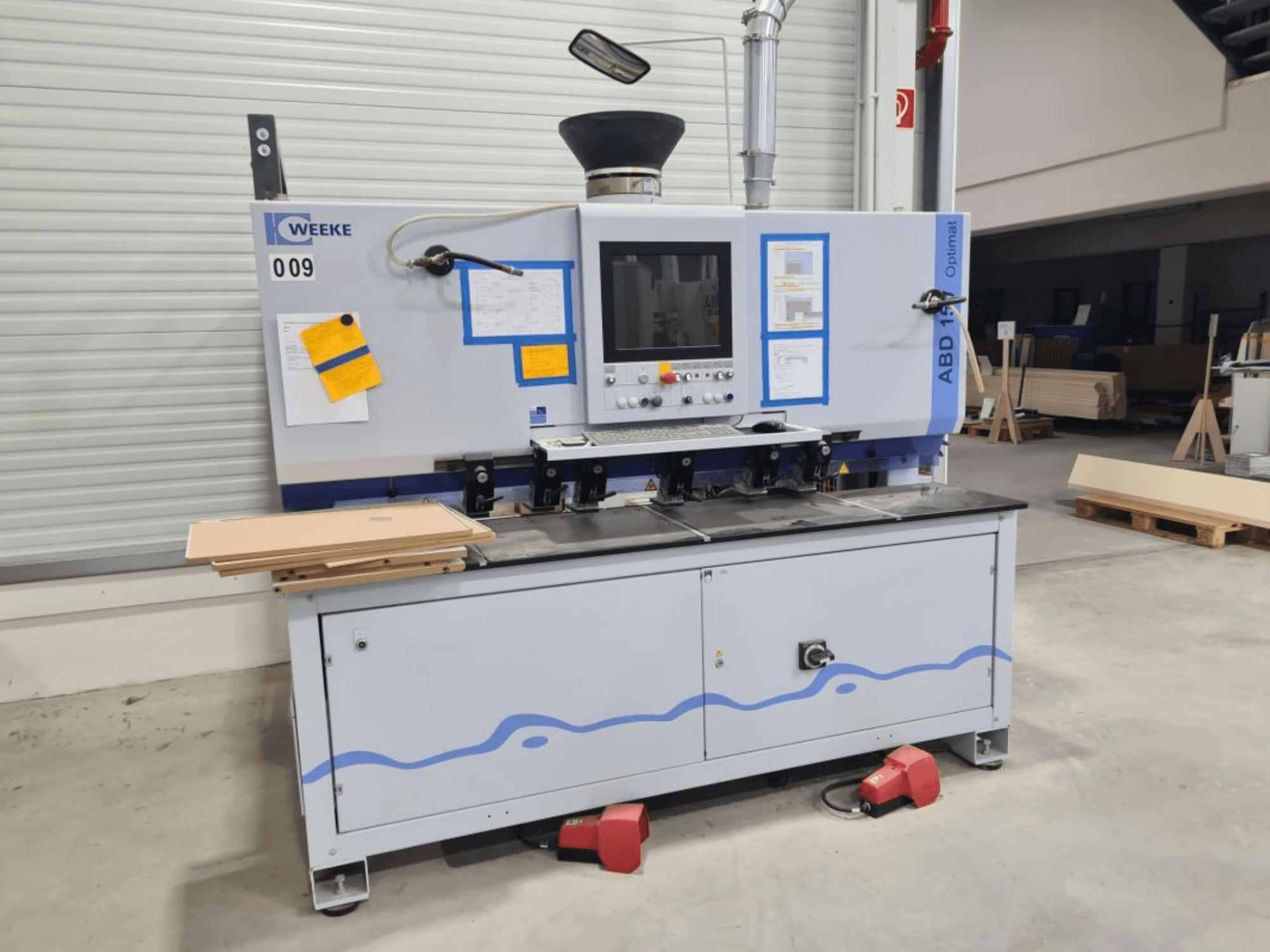 Багатошпиндельний свердлильний верстат HOMAG WEEE OPTIMAT ABD150, вид спереду, показані елементи керування та складені дерев'яні панелі.